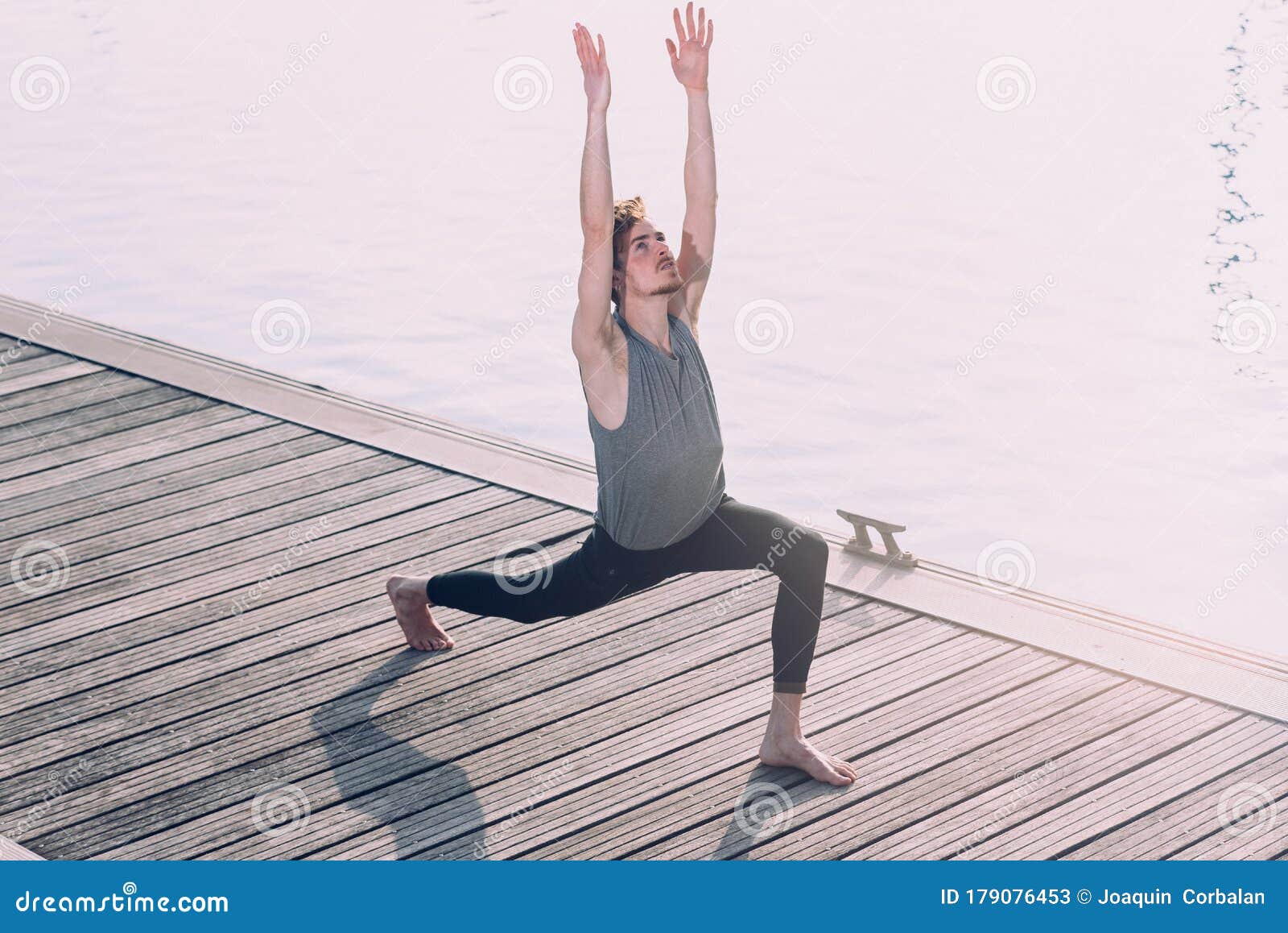 young sportsman performing articular movements of yoga in an urban area of the city