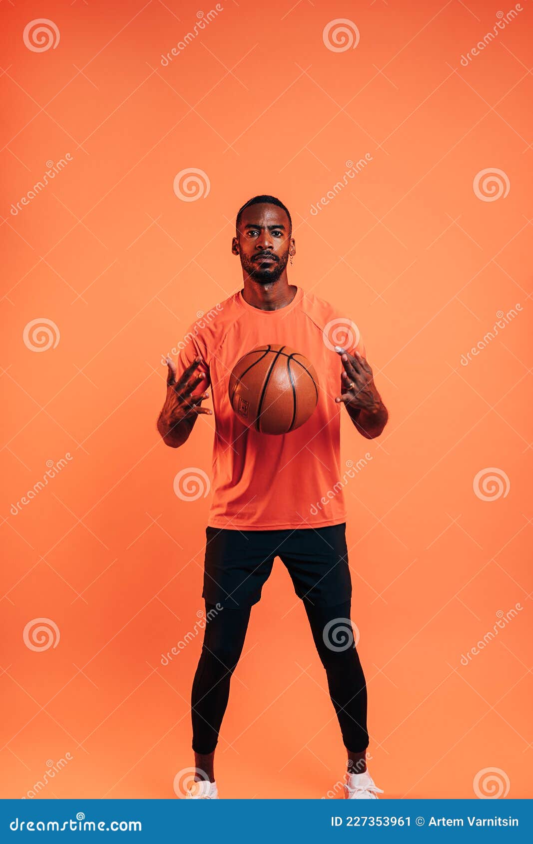 Young Sportsman Throws the Ball into the Air in Front of Him in Studio