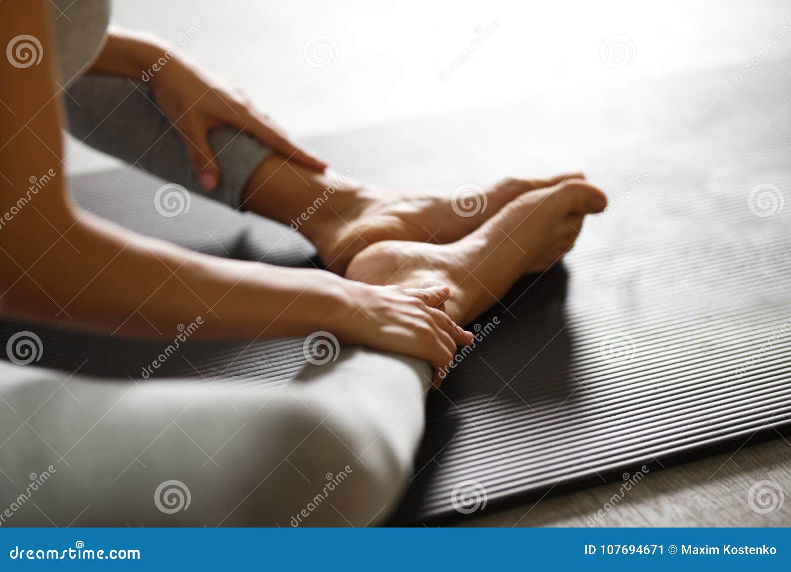 young sporty woman doing yoga stretching exercise sitting in gym near bright windows
