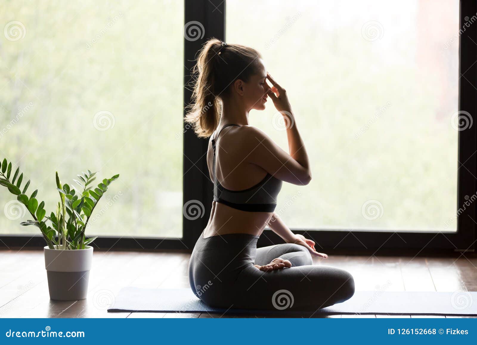 young sporty woman practicing alternate nostril breathing