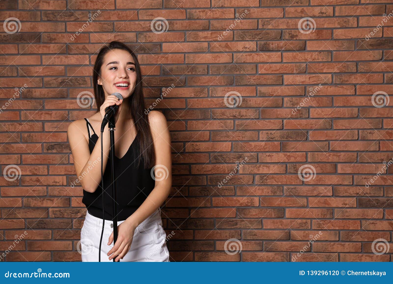 Young Stylish Woman Posing with Microphone Near Brick Wall. Stock ...