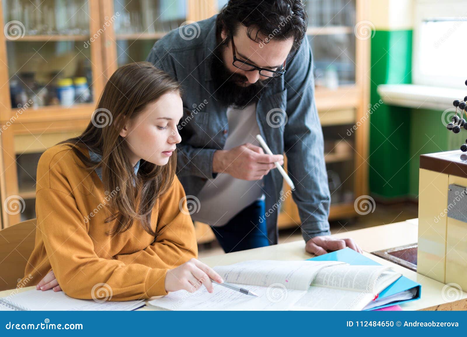young teacher helping his student in chemistry class. education and tutoring concept.