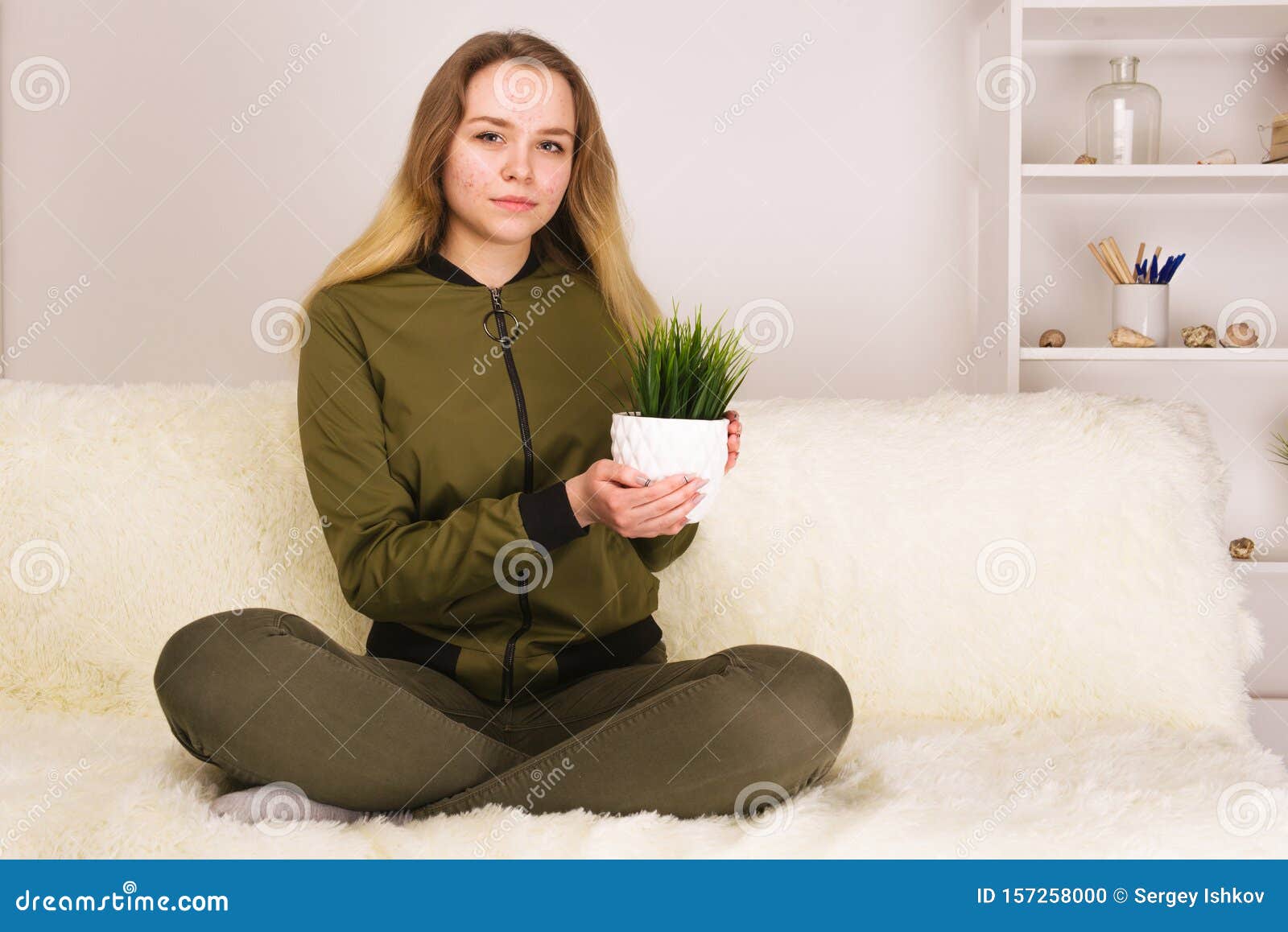 Young Teen Girl With Acne Face Sitting On Sofa And Holding Green