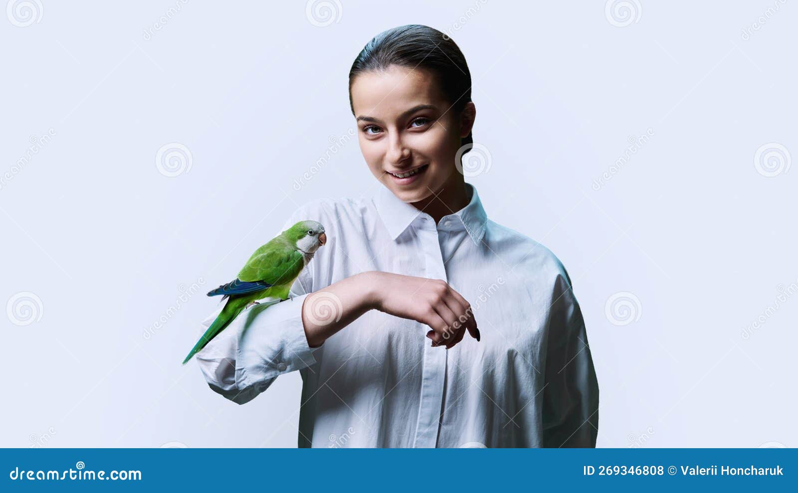 young teenage female with green pet parrot, on white background