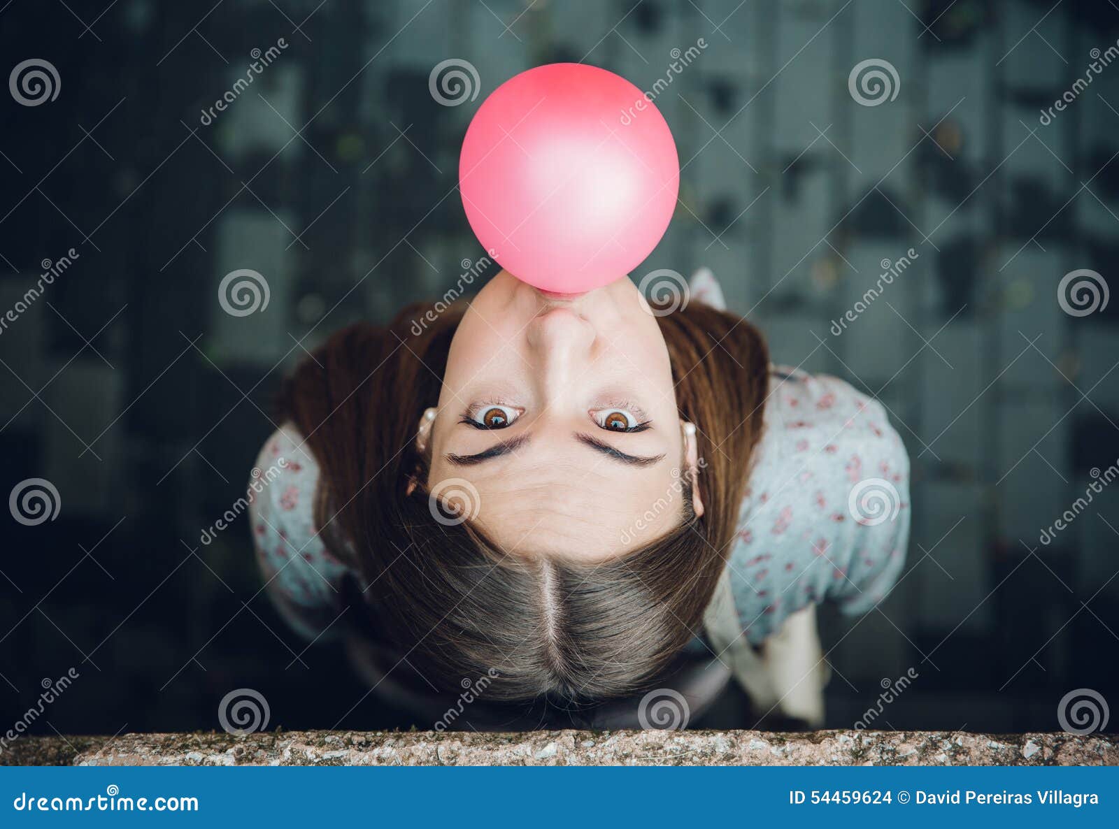 Young teenage girl blowing pink bubble gum. Top view of beautiful young brunette teenage girl blowing pink bubble gum