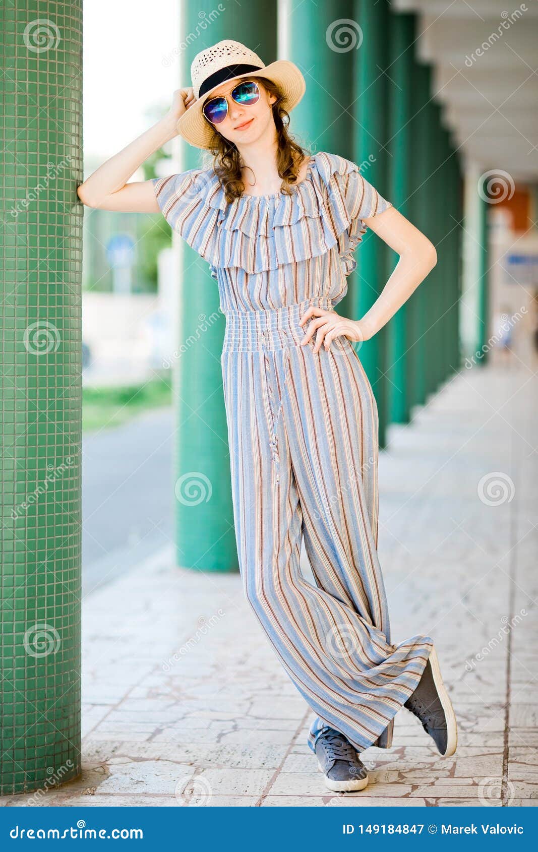 Fashionable Shot Of A Young Woman In A Summer Blue Jumpsuit With A Bright  Print Poses In The Studio, Long Legs Stock Photo, Picture and Royalty Free  Image. Image 80995517.