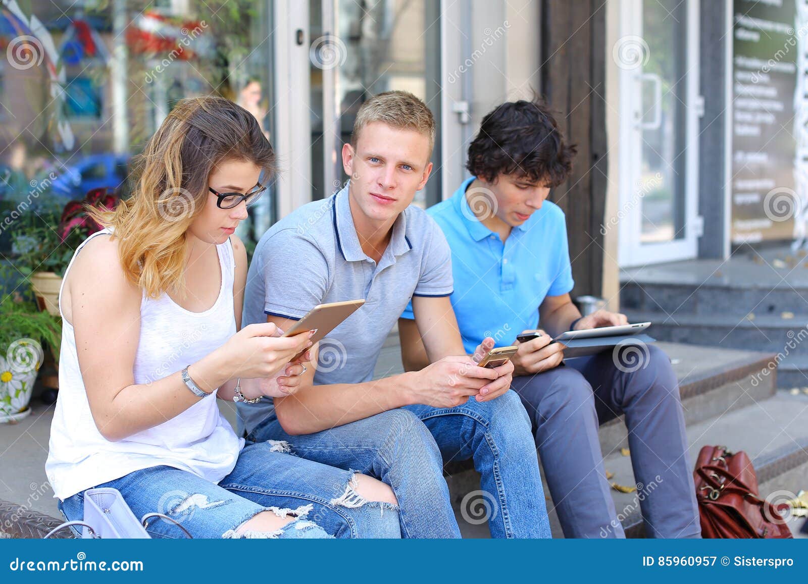 Друзья сидящие в телефоне. Трое друзей болтают на улице. Люди разговаривают на улице. Фотомодели в феврале на улице болтают. Люди остановились на улице и разговаривают.