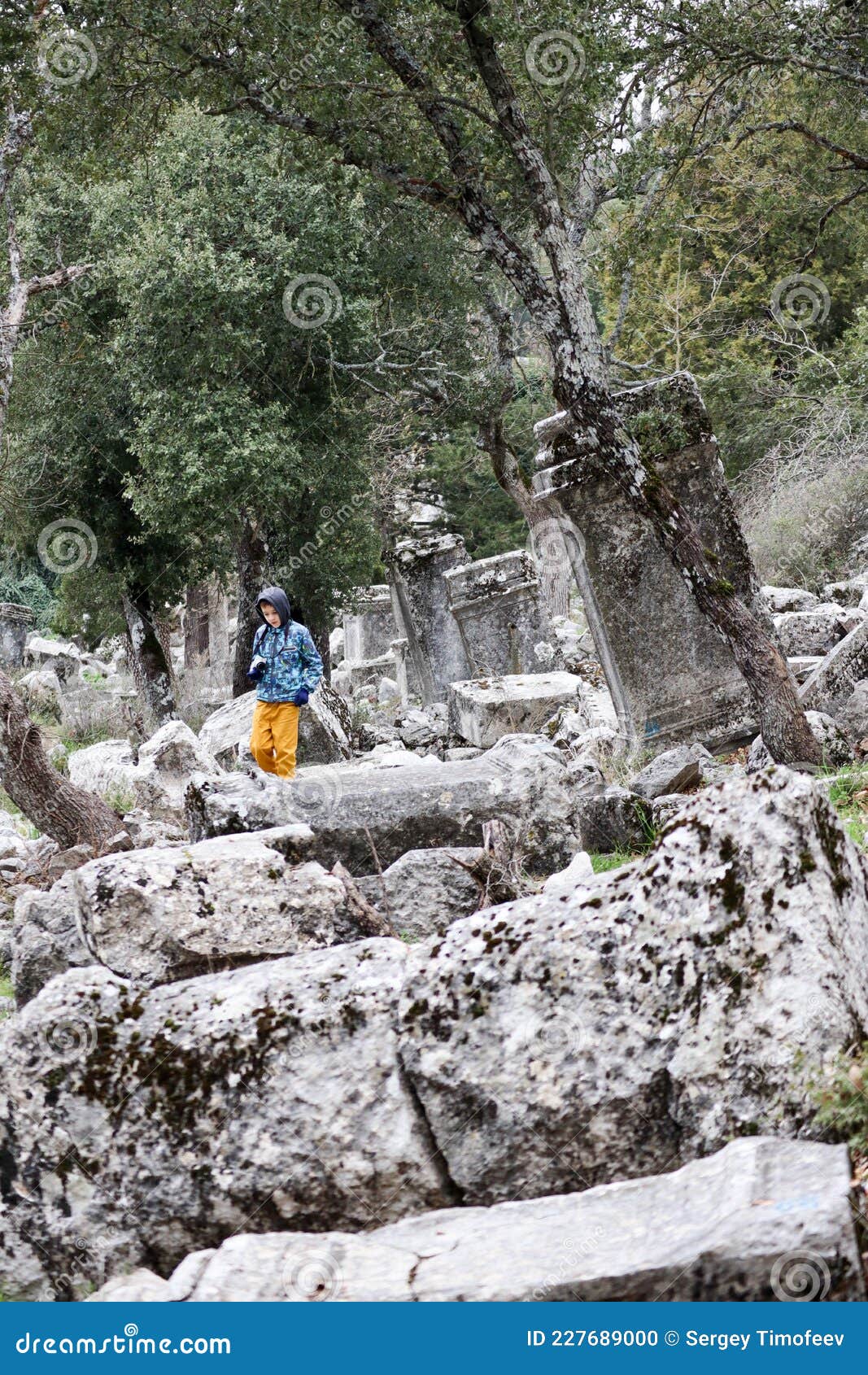 young tourist boy with camera explore the ancient abandoned pisidian city termessos in turkey