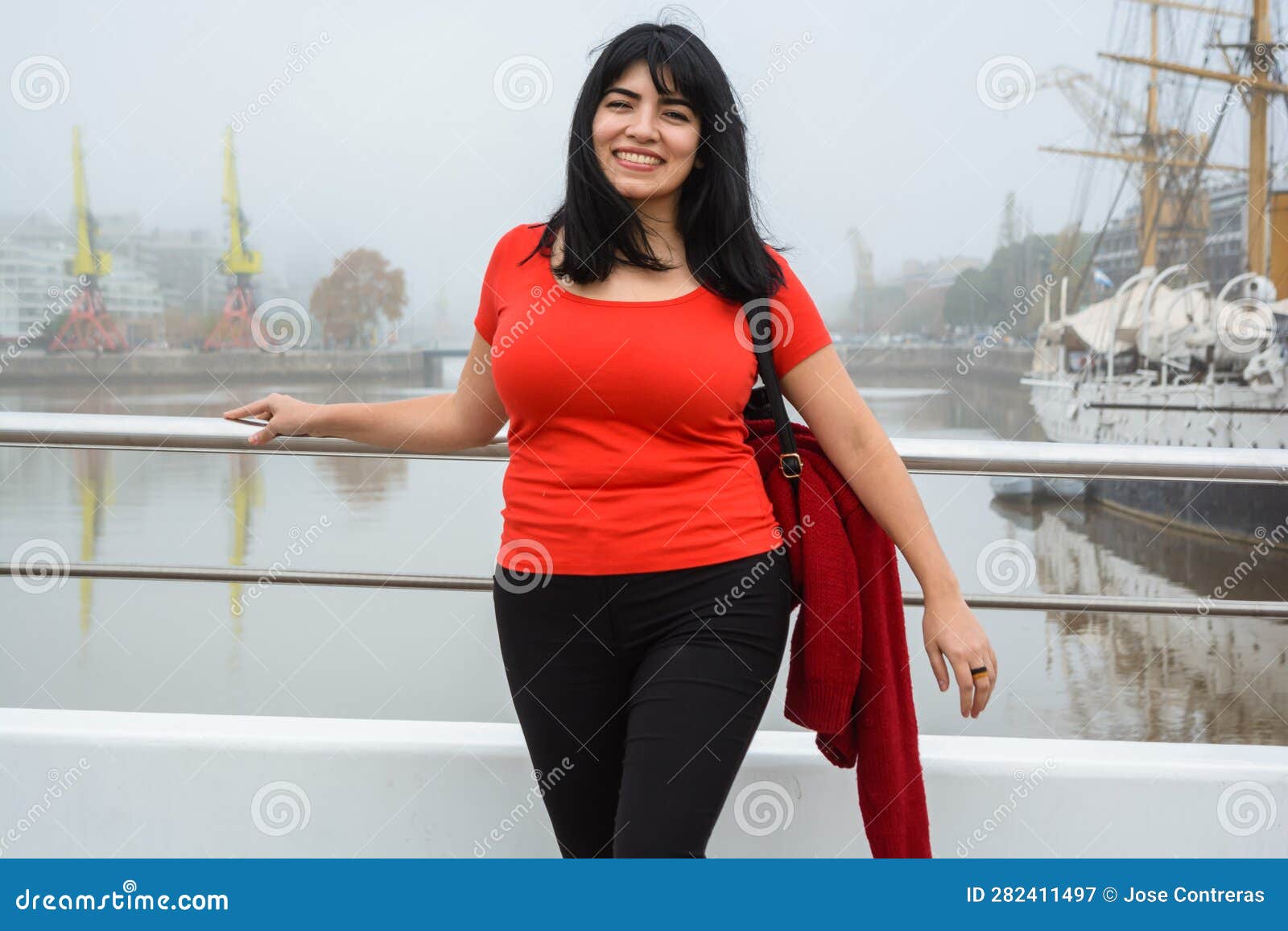 young tourist standing looking at the camera on the puente de la mujer on a cloudy day with mist