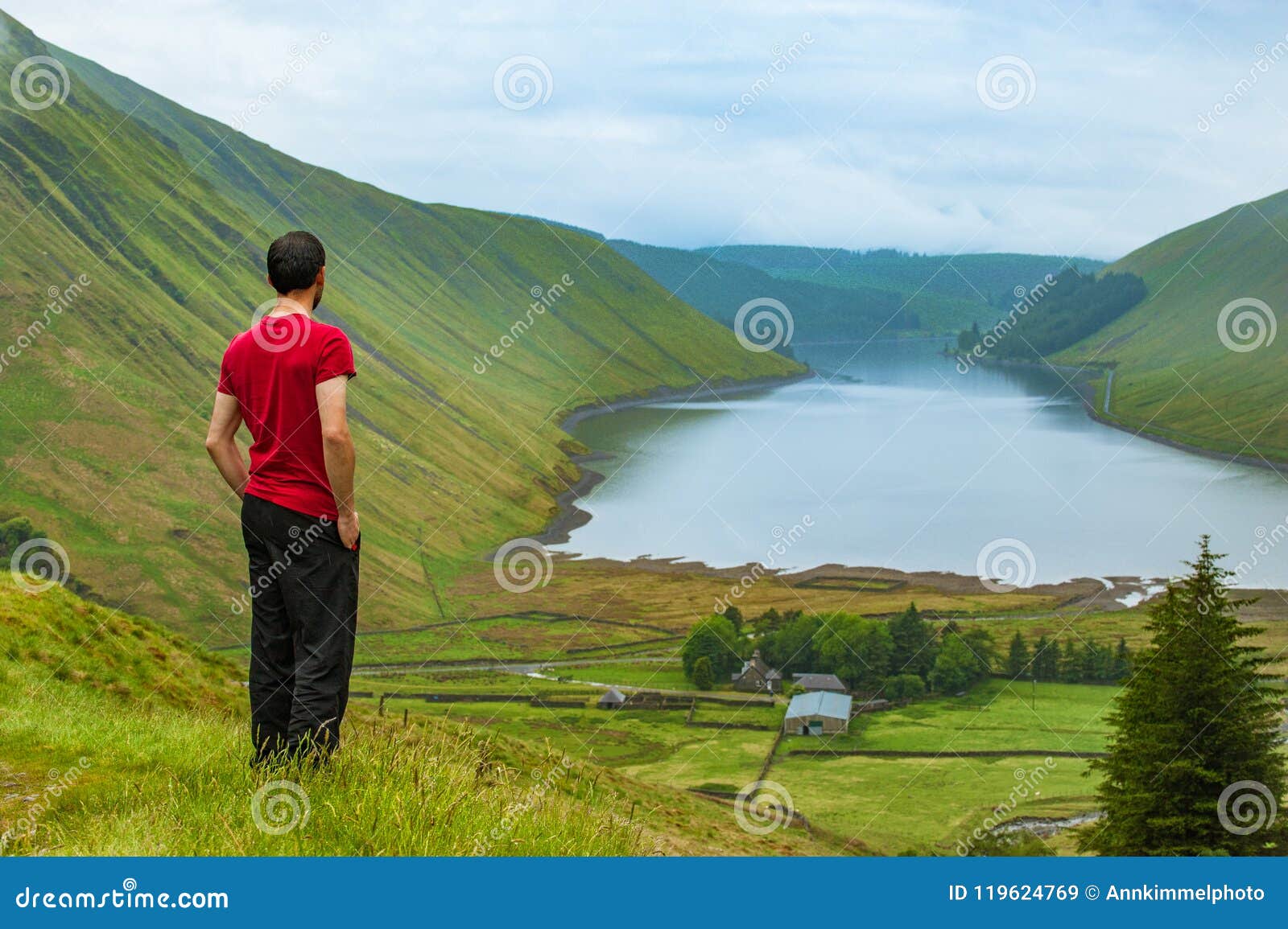 A Young Traveller Man Observing a Lake in a Deep Valley Covered