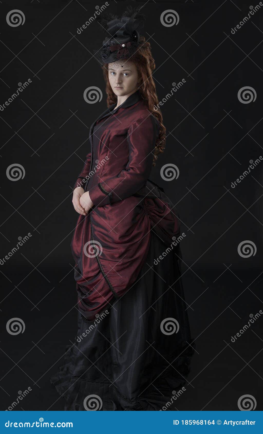 a young victorian woman in a dark red and black ensemble