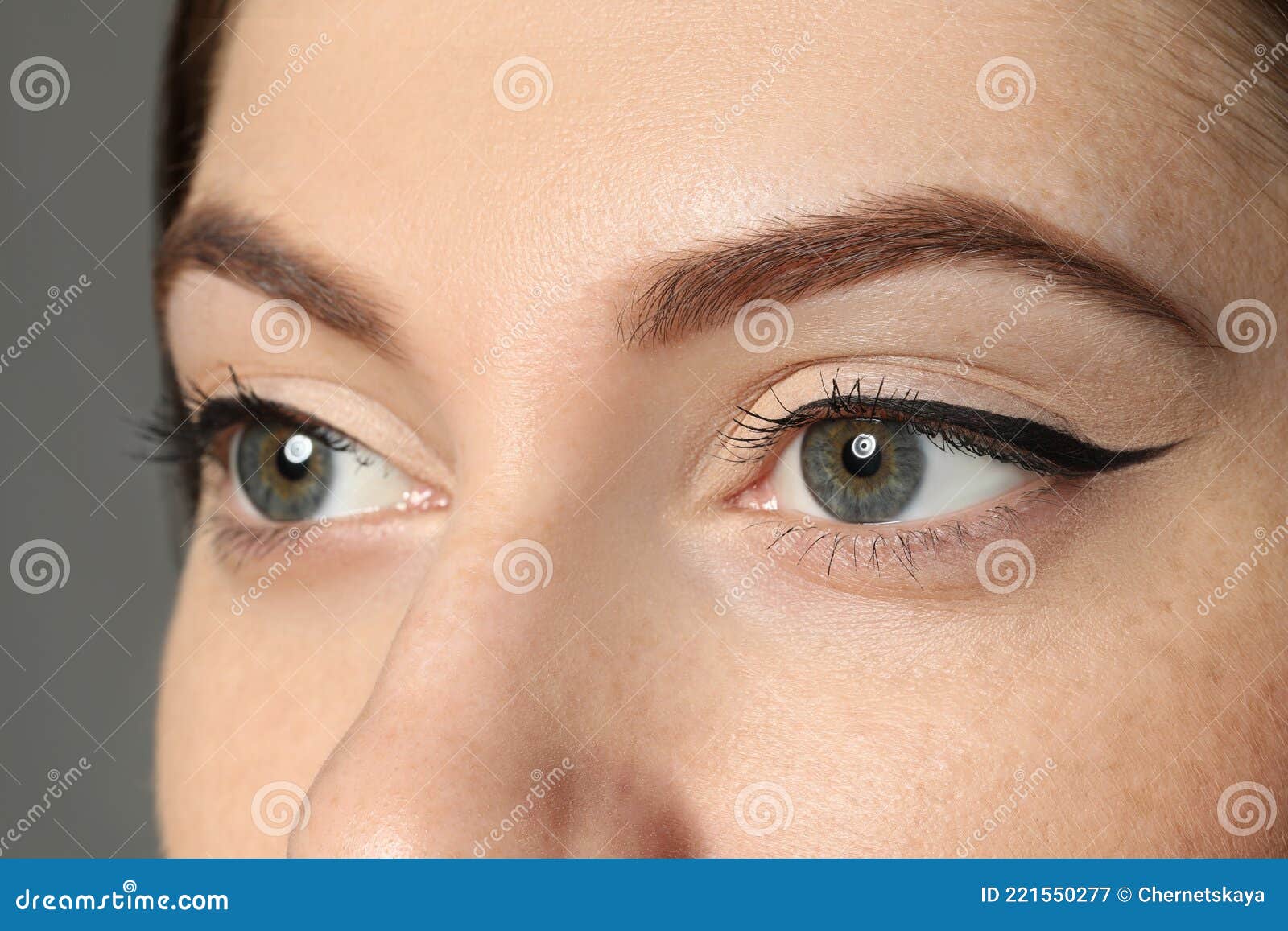 young woman with eyebrows on grey background, closeup