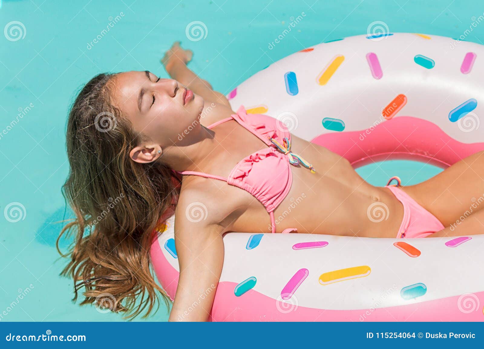 Young Women In Bikini Swim On Inflatable Ring Donut And Has Fun In