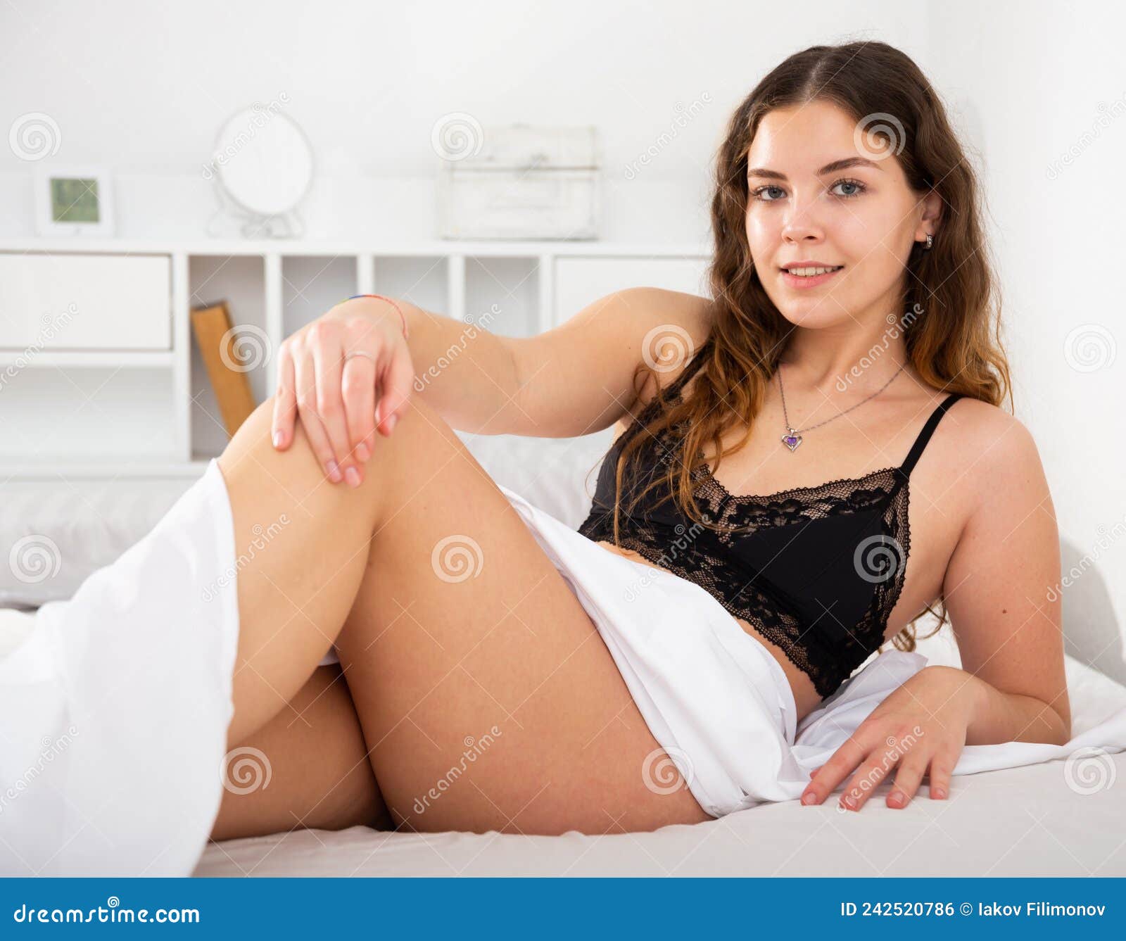 Young Woman in Black Bra and Panties Lying on Bed Stock Photo