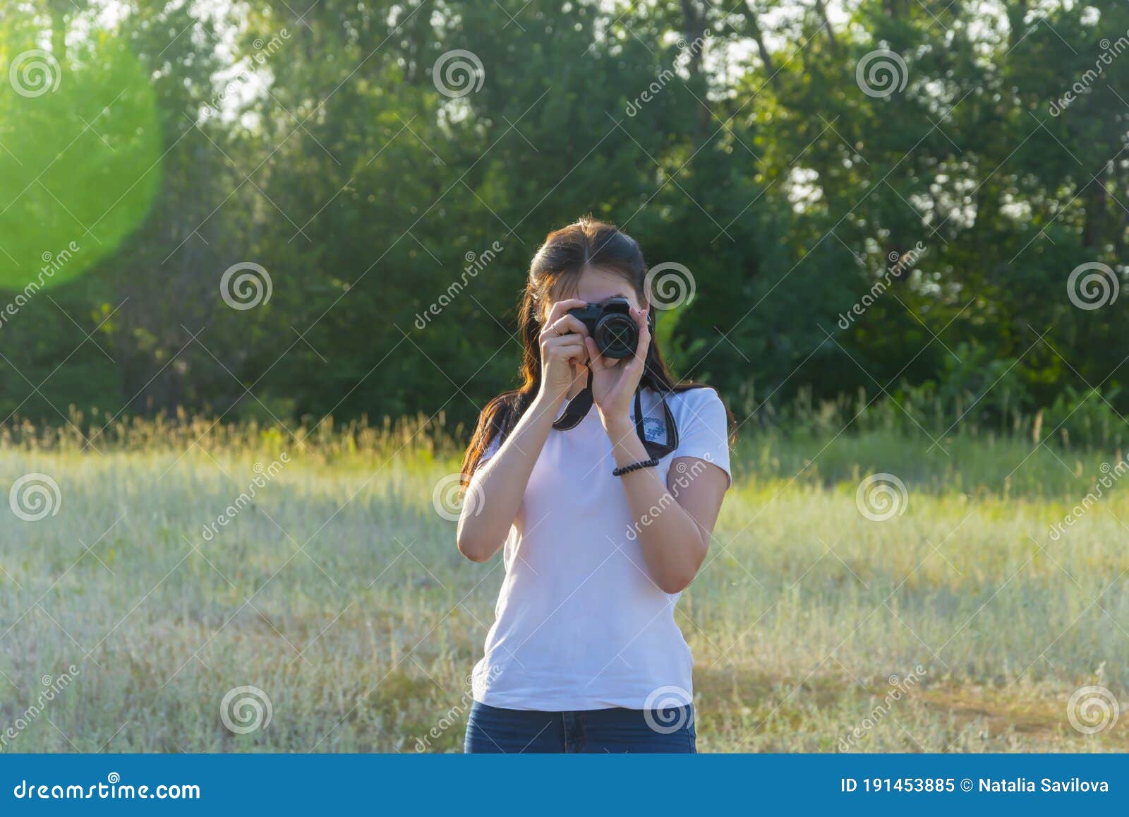 young woman with camera lens. a beautiful brunette photographer is taking pictures in nature on a summer day