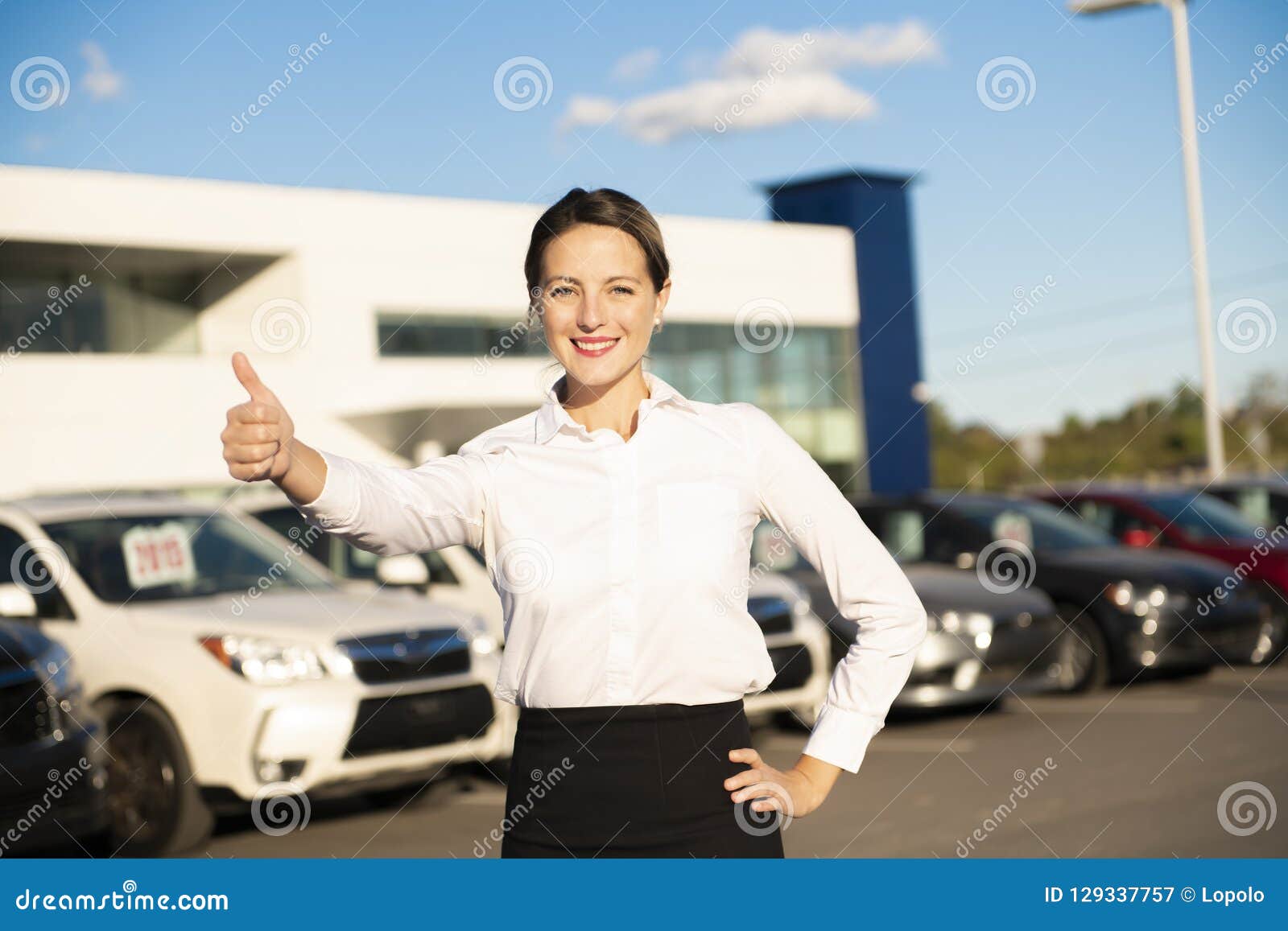 Young Woman Car Rental In Front Of Garage With Cars On The Bac