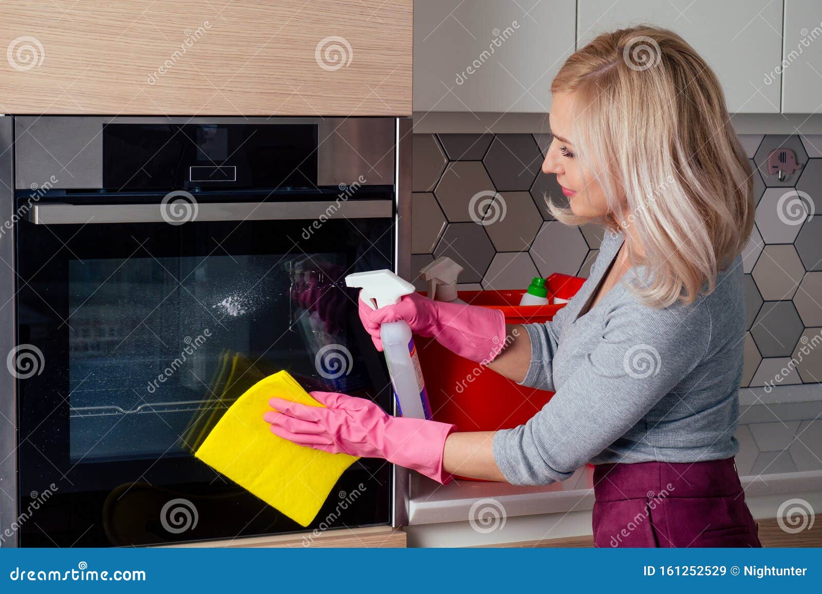 young woman cleaning oven in the kitchen