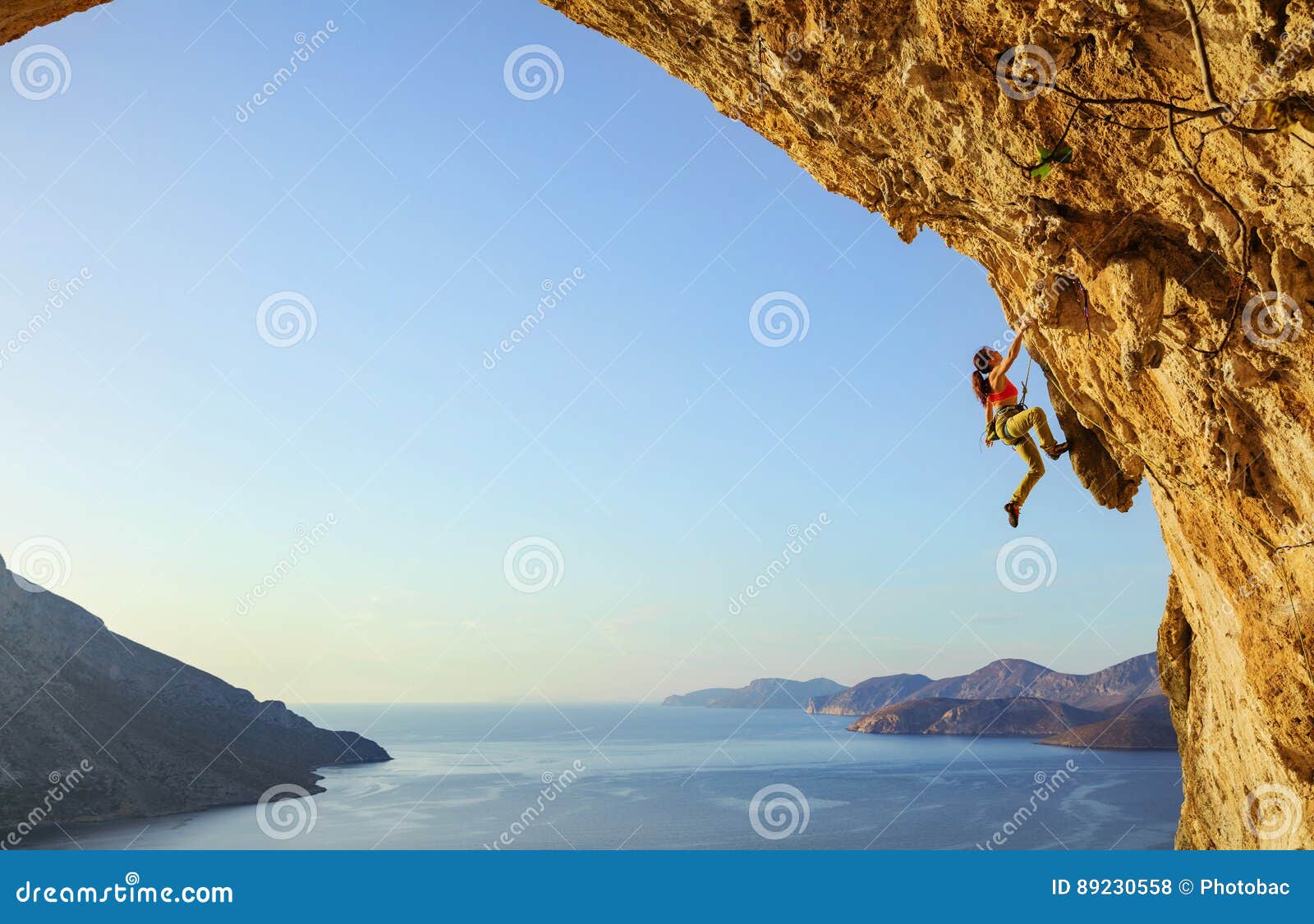 young woman climbing challenging route in cave at sunset