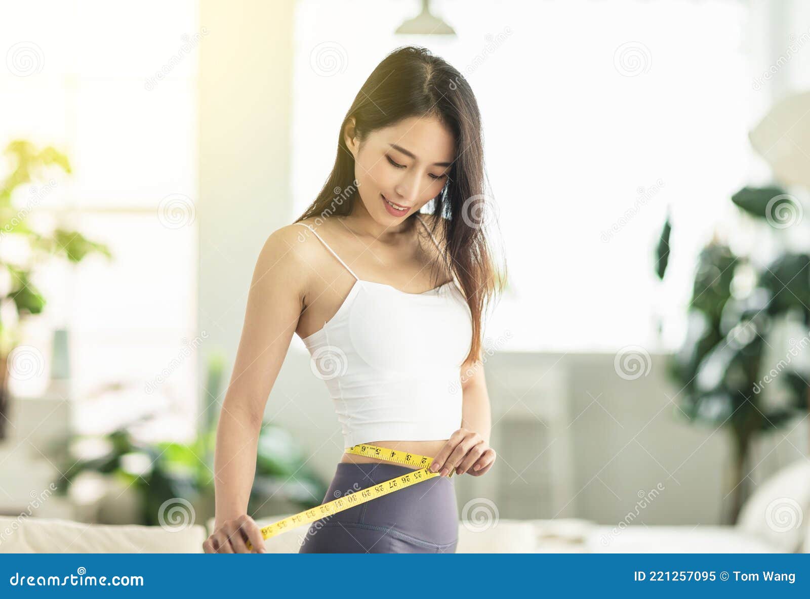 a young woman at home confidently measured her waist circumference, satisfied with her posture, and very happy to lose weight