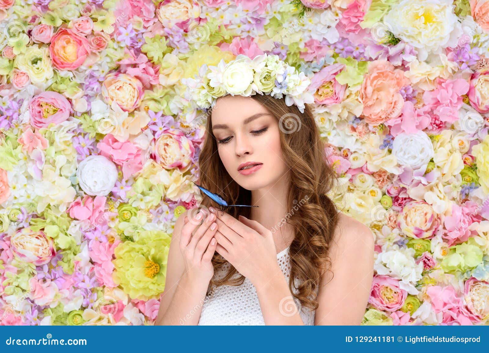 young woman with curly hair in floral wreath with butterfly