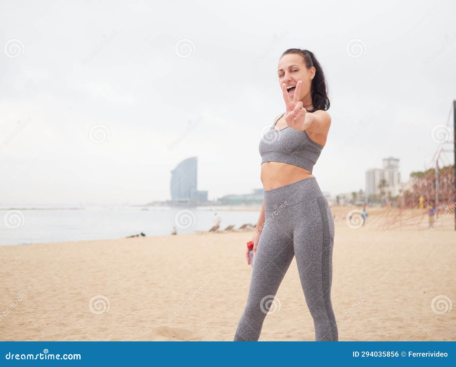 young woman doing stretching at playa de la barceloneta - barcelona spain.