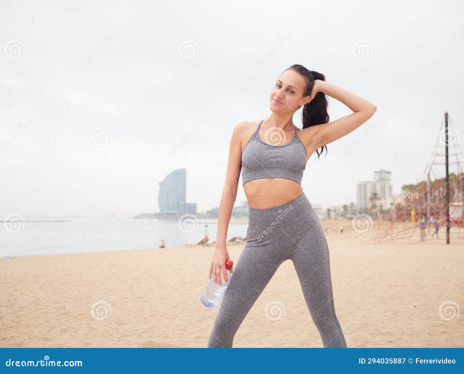young woman doing stretching at playa de la barceloneta - barcelona spain.