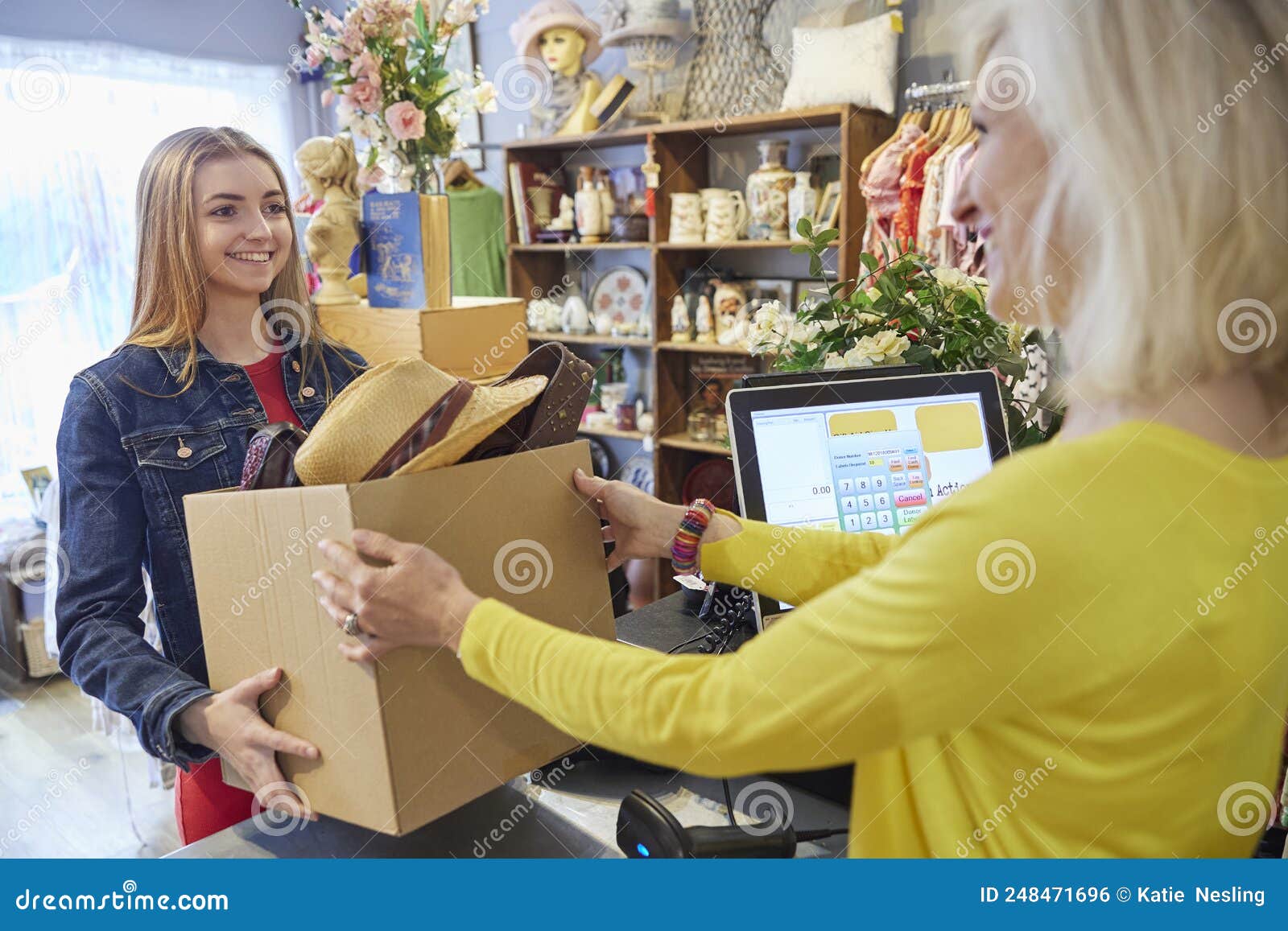 young woman donating items to volunteer ar charity or thrift shop