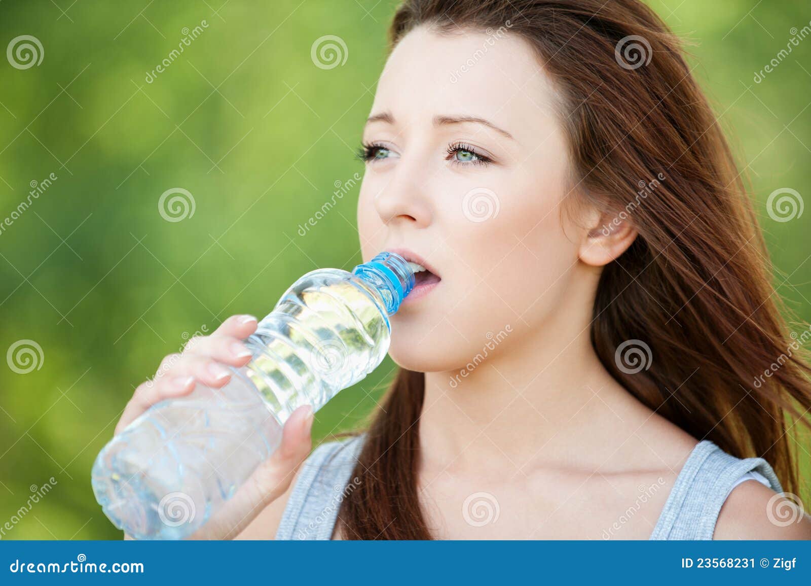 Young skinny girl drinking clean water from bottle in 