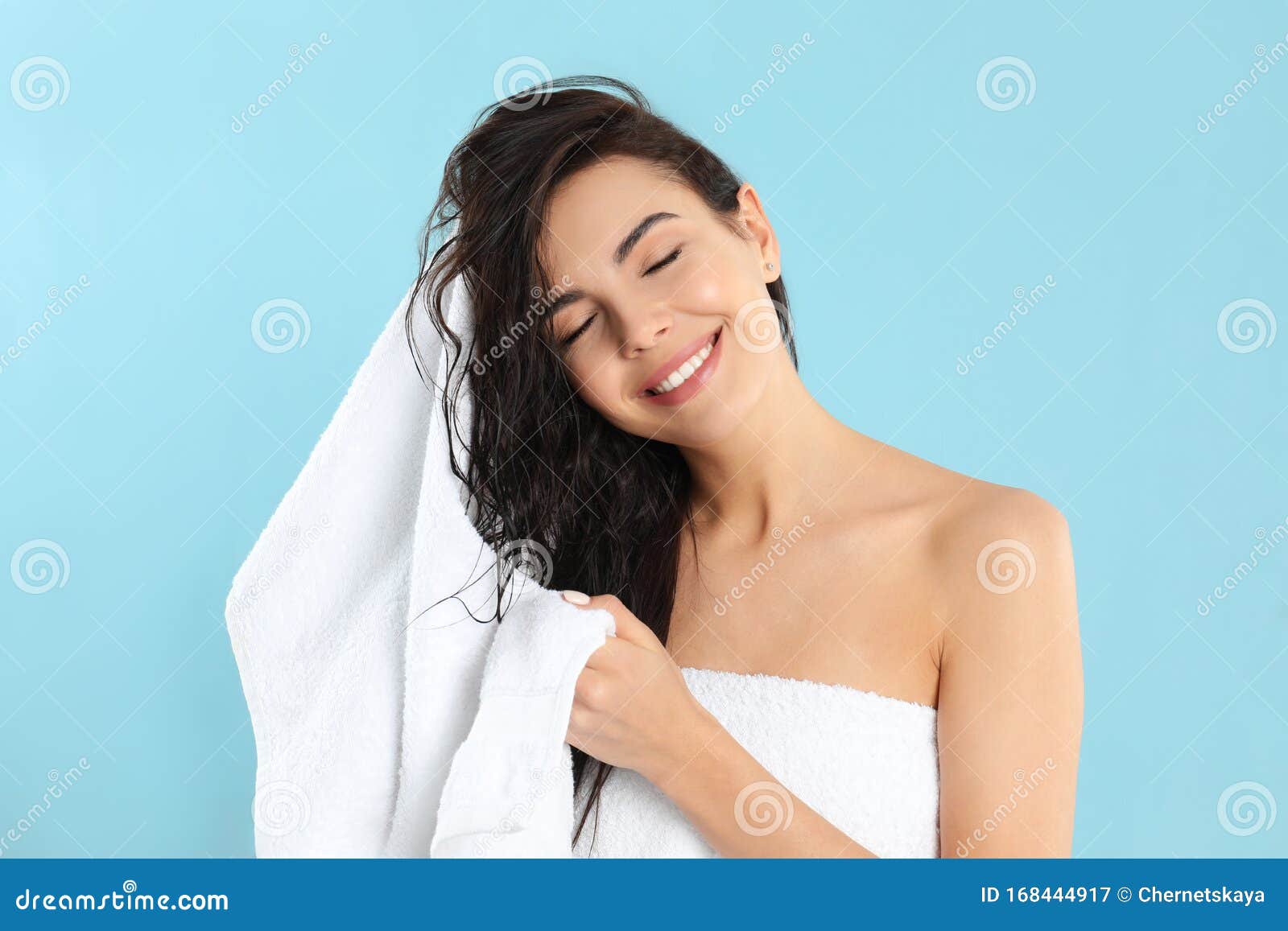 young woman drying hair with towel on blue background