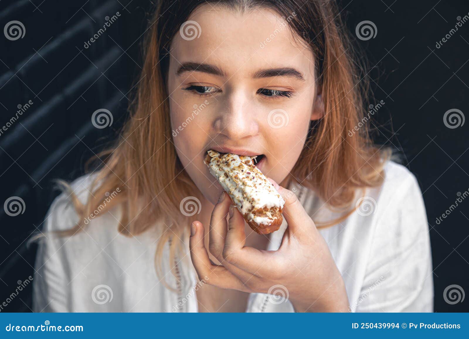 A Young Woman Eats an Appetizing Eclair. Stock Photo Image of nutrition, natural 250439994