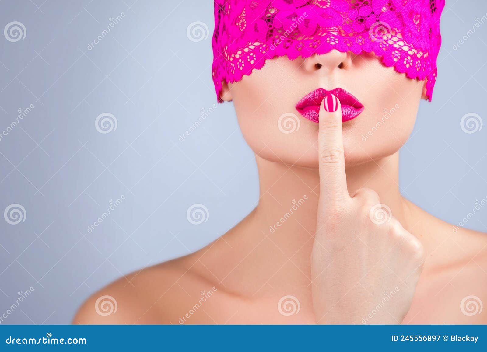 Close-up of a woman's face in elegant lace blindfold, finger to lips in sensual hush, intimate and mysterious mood
