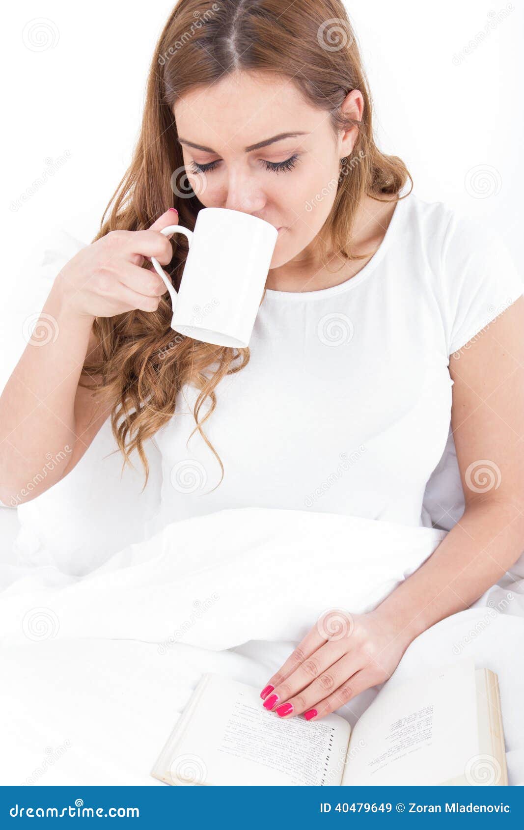 Young Woman Enjoying Reading And Drinking Coffee In Bed Stock Image