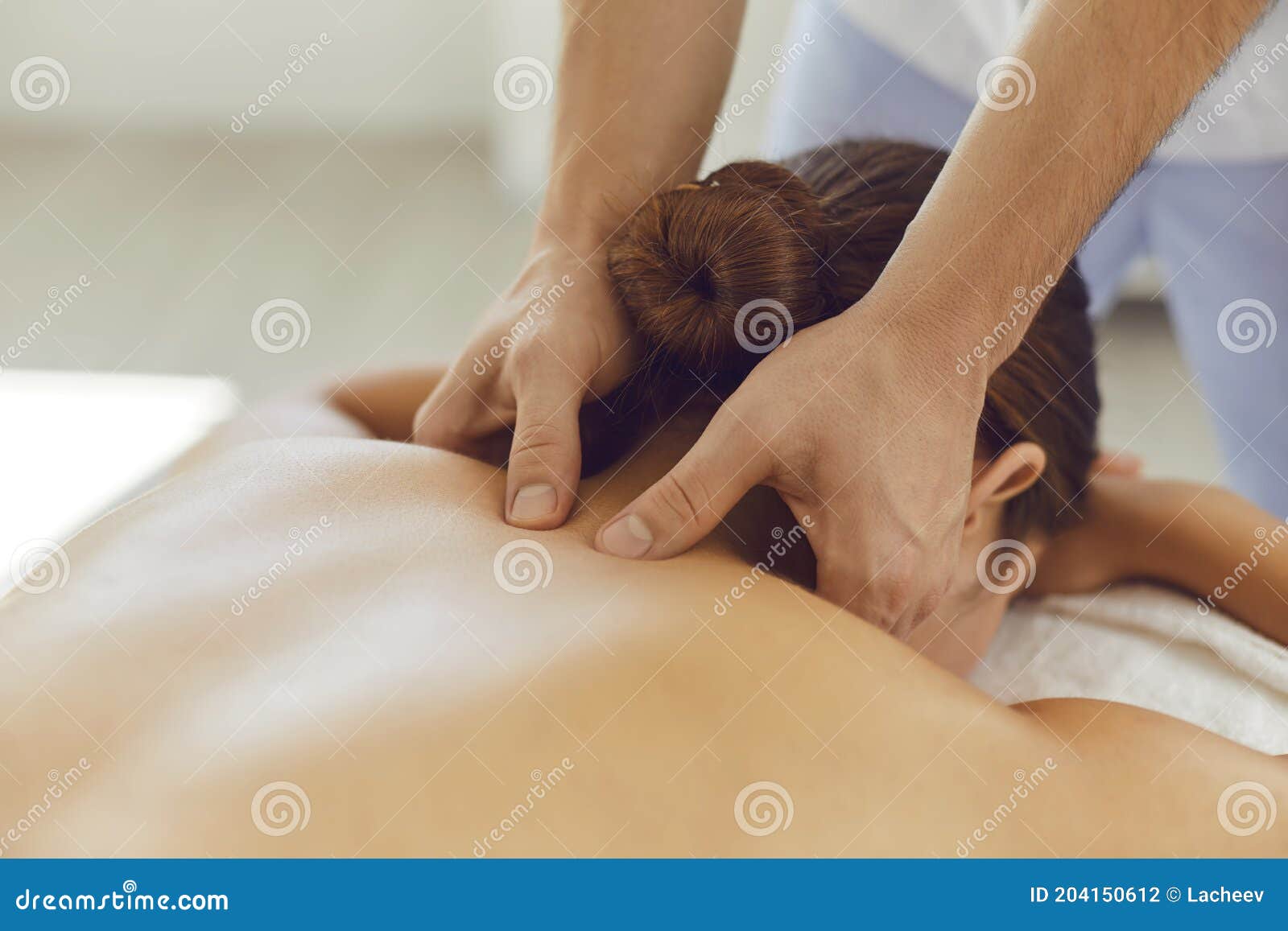 young woman enjoying relaxing remedial body massage done by professional masseur