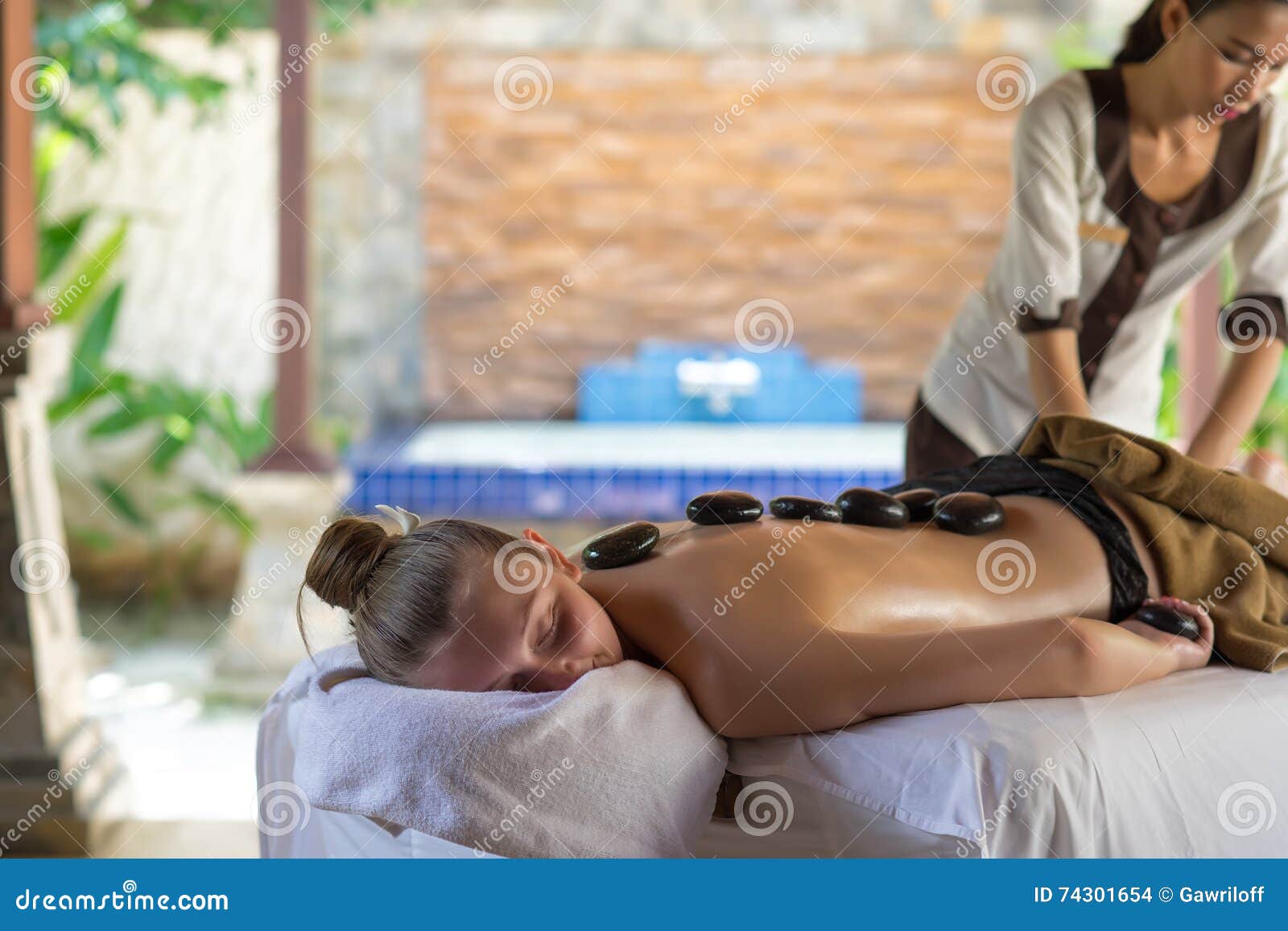 Young Woman Getting Hot Stone Massage in Spa Salon