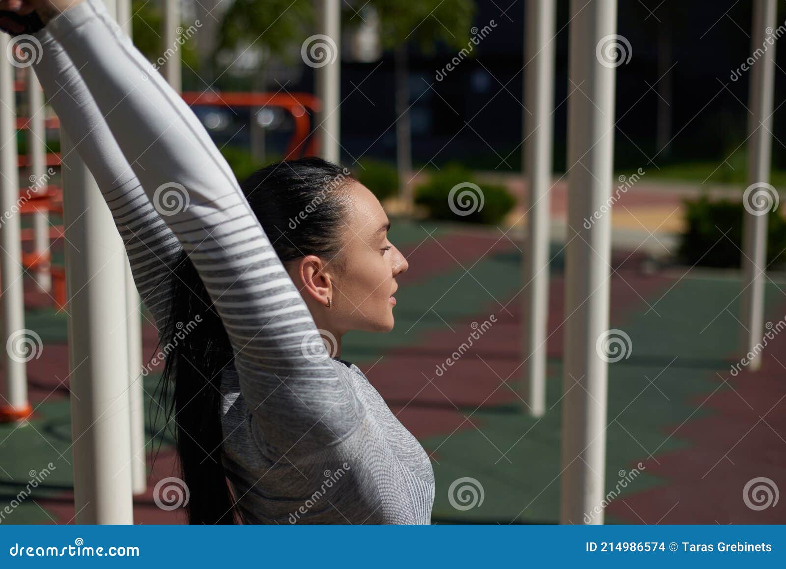 A Young Woman in a Gray Tracksuit Does Stretching with Her Hands Up ...