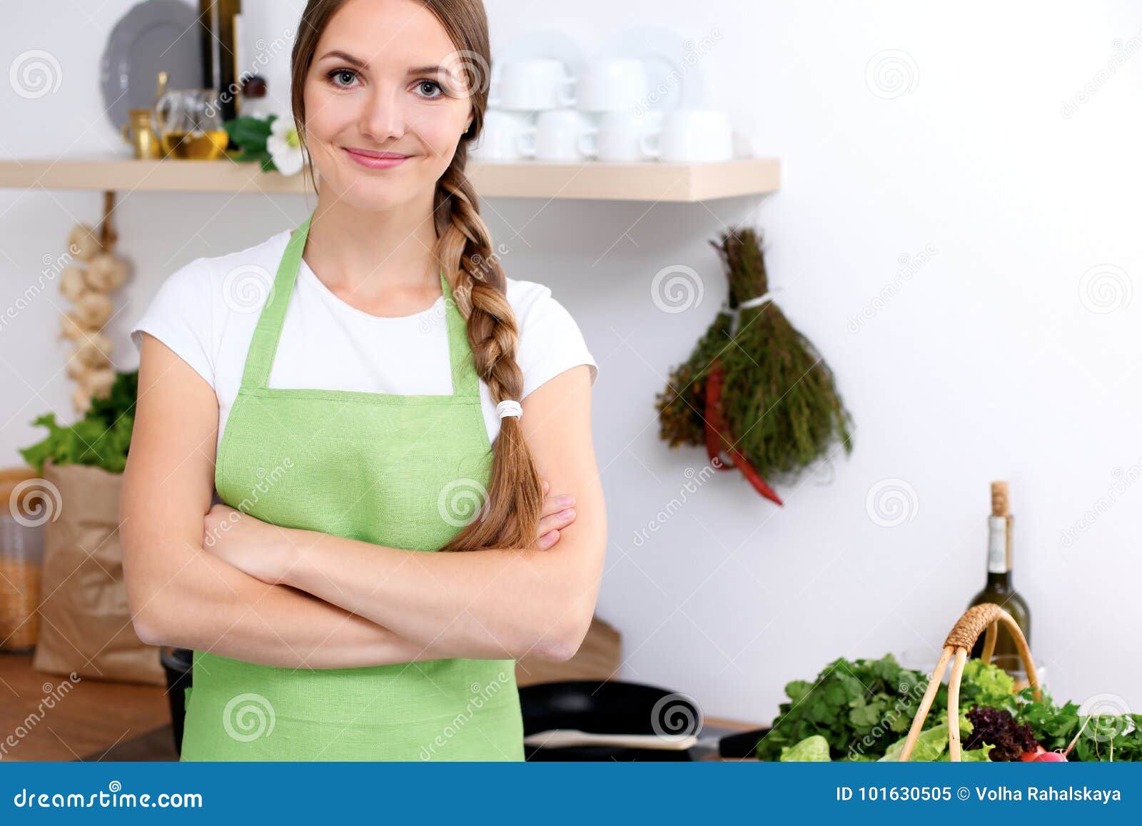 young woman in green apron is going for cooking in a kitchen. housewife is tasting the soup by wooden spoon.