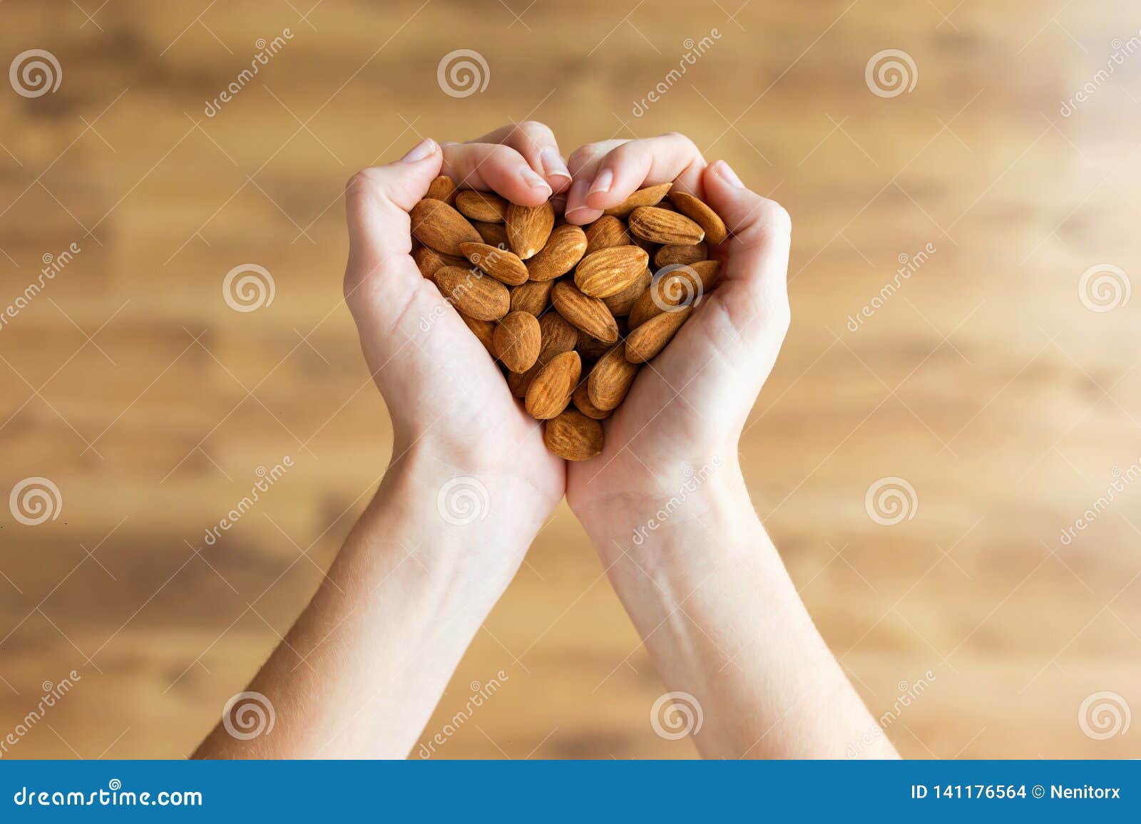 young woman hands forming heart  holding almonds nuts at home