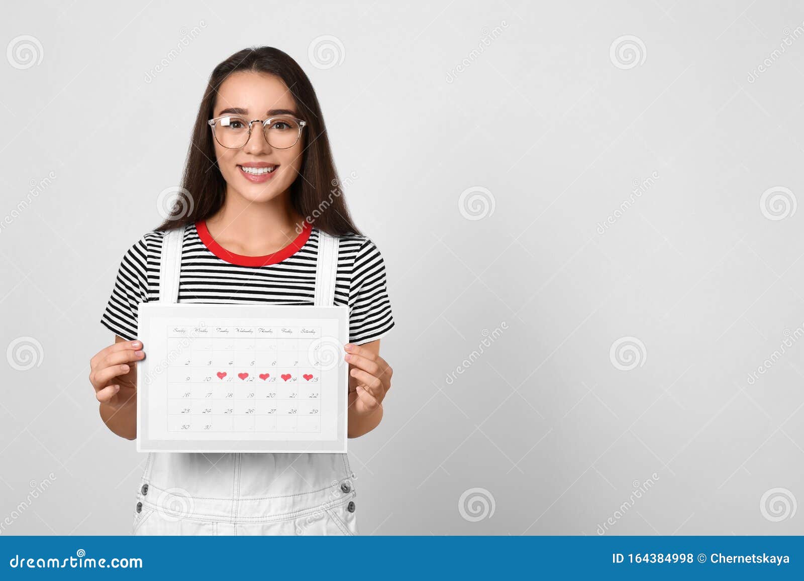 Young Woman Holding Calendar With Marked Menstrual Cycle Days On