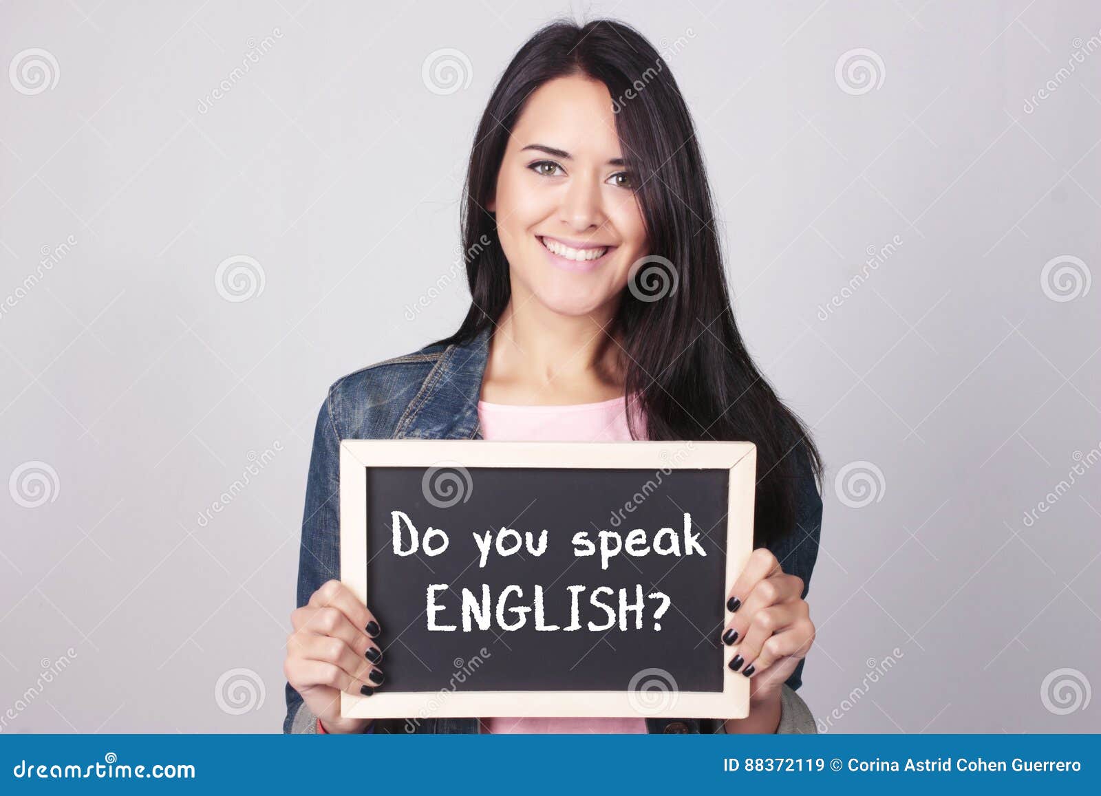 young woman holding chalkboard that says do you speak english?