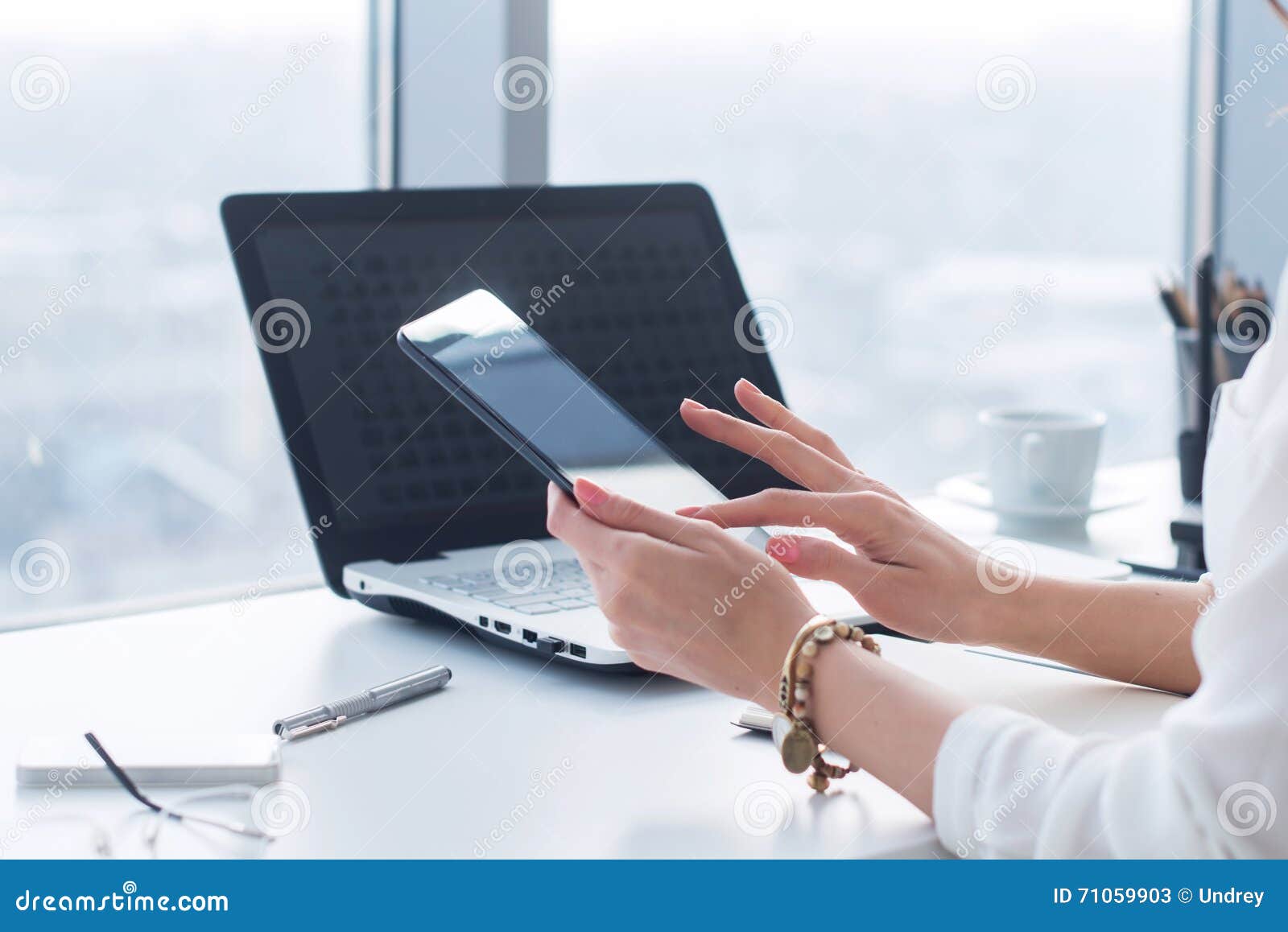 young woman holding modern tablet computer, using device at workplace during break, chatting, blogging and posting