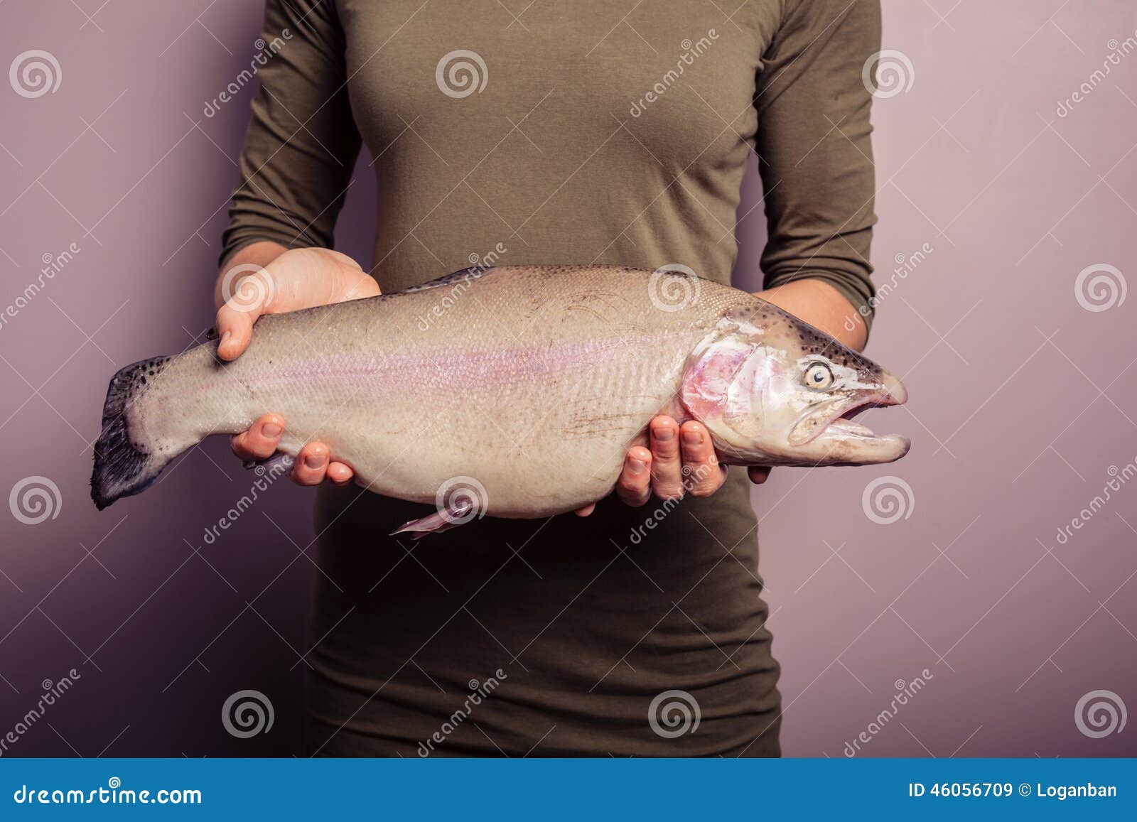 A young woman in a cowboy hat holding a fish net shows a cutthroat trout.  stock photo