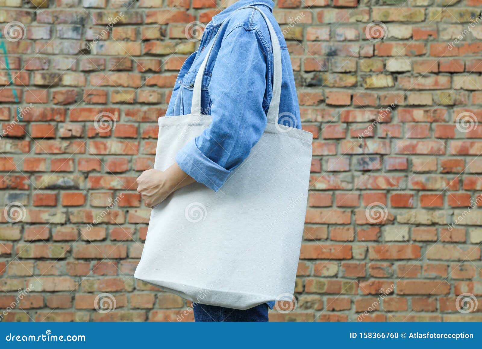 Young Woman Holding Tote Bag Against Brick Wall Stock 