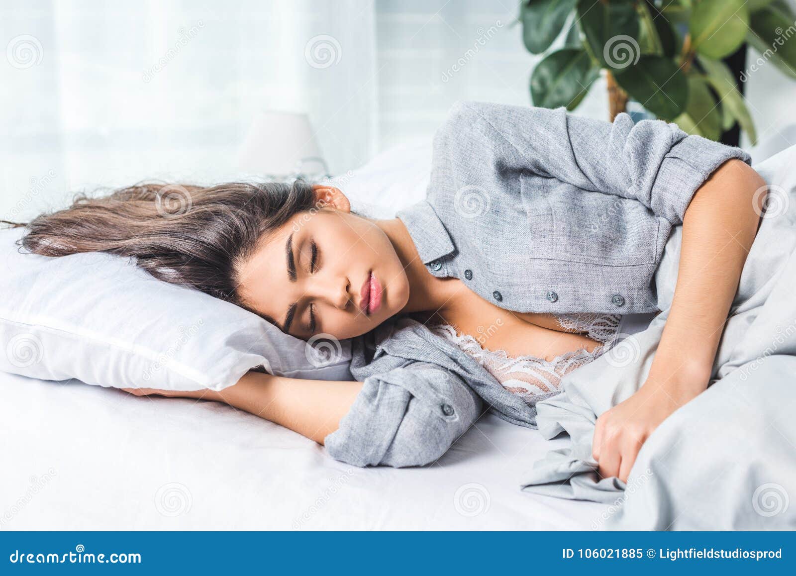 sensual brunette young woman in black bra sleeping on bed Stock Photo