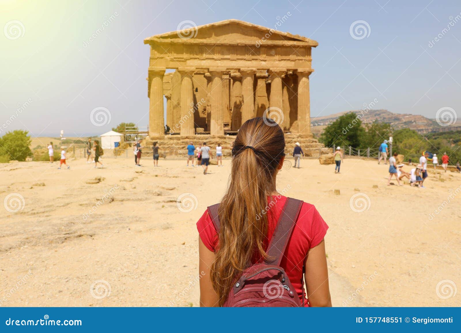 young woman looks at concordia temple in the valley of the temples of agrigento, sicily. traveler girl visits greek temples in