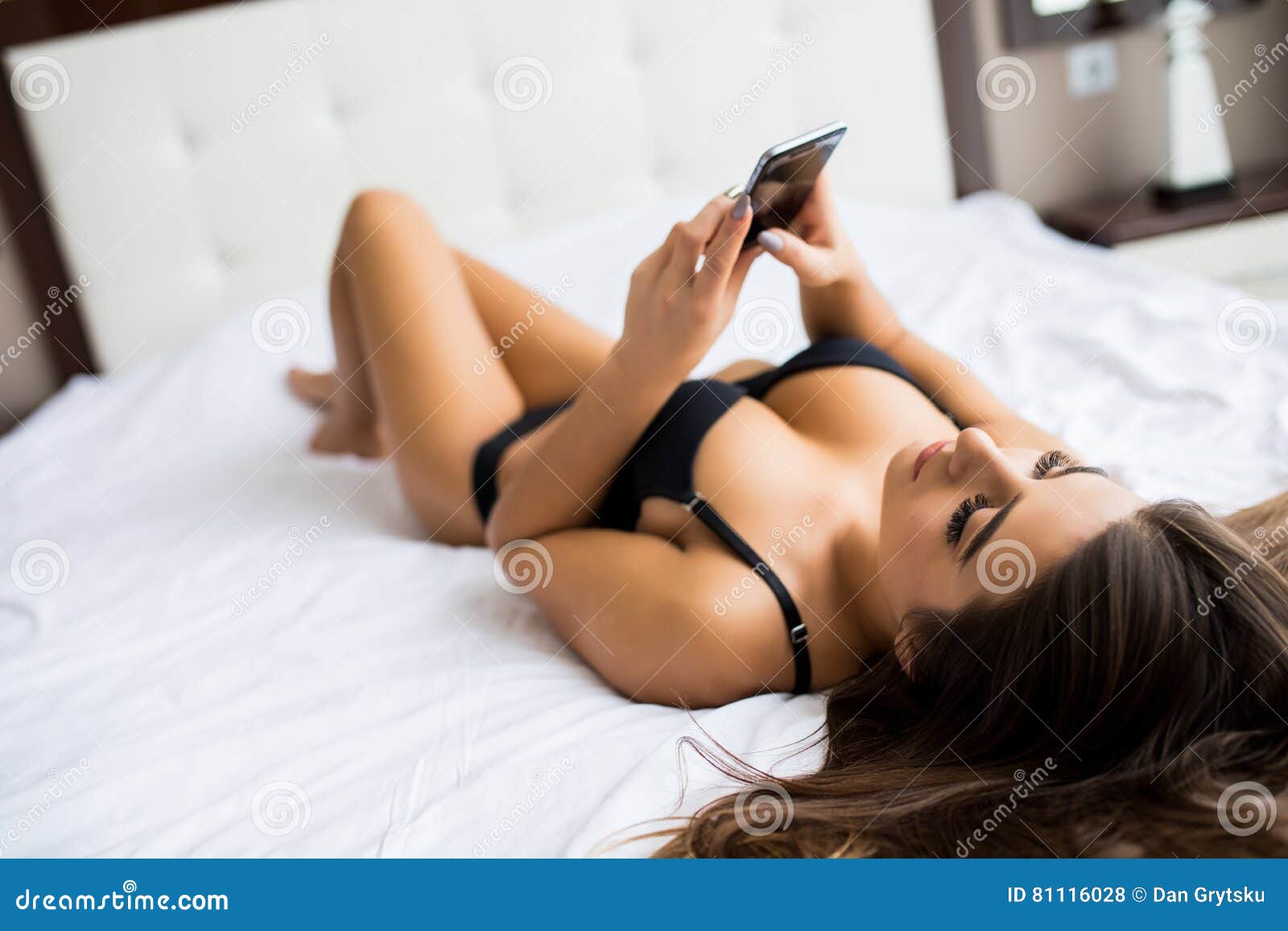 Young Woman Lying on Her Bed and Taking Selfie Stock Photo