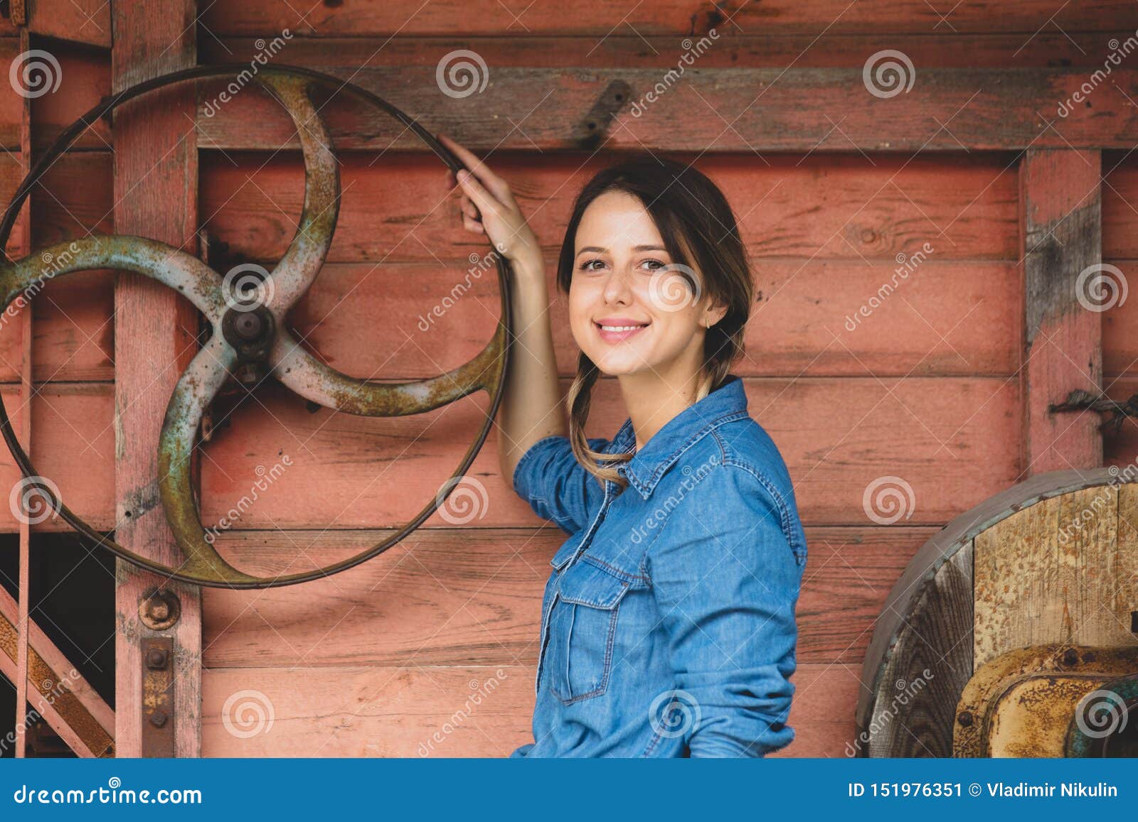 young woman near wheel of an old wooden combine harvester of xix century