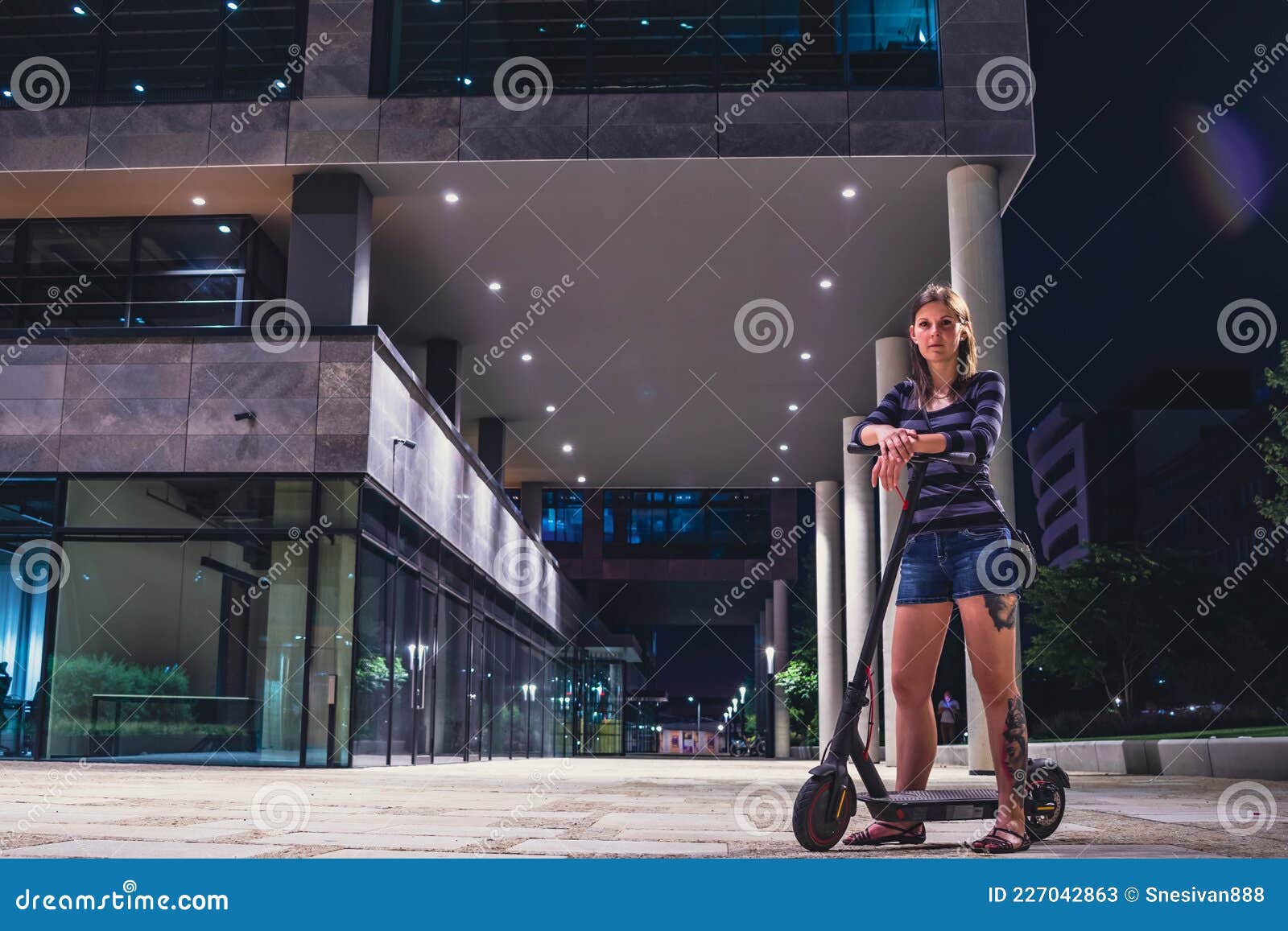 young woman at night on a scooter in the busines center