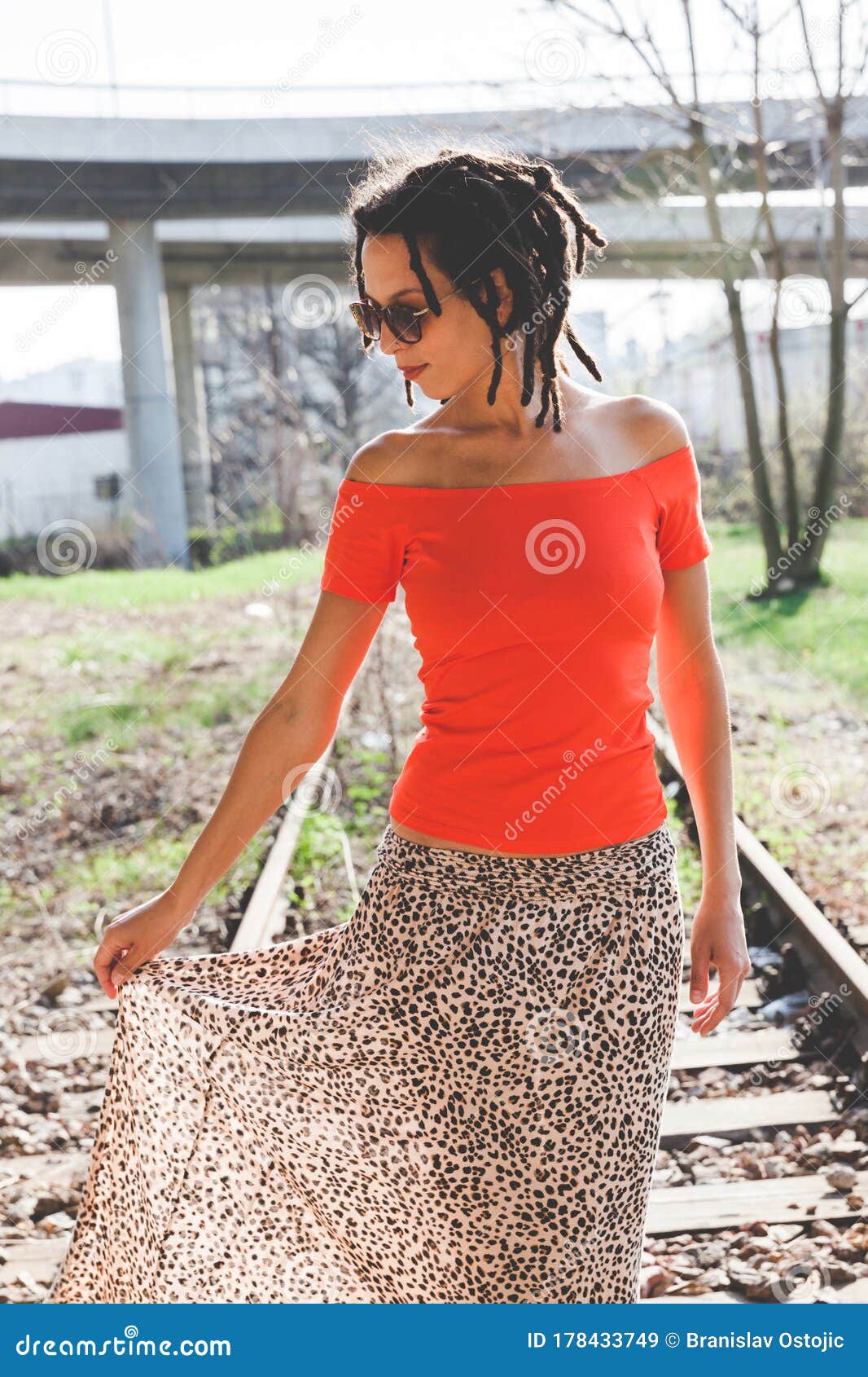 Young Woman in Orange T Shirt and Long Skirt with Dreadlocks