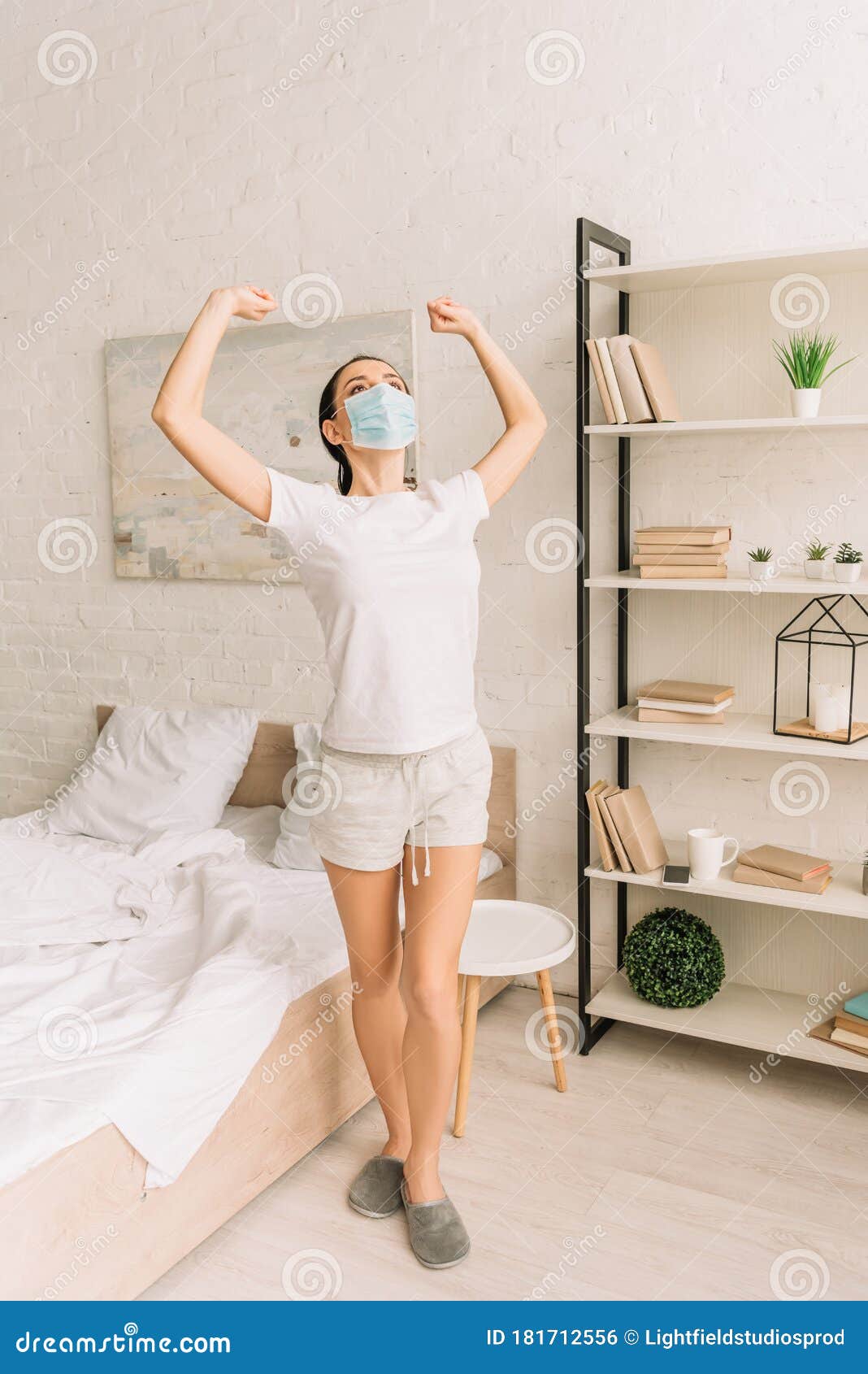 Woman in Pajamas and Medical Mask Stretching Hands in Bedroom Stock ...