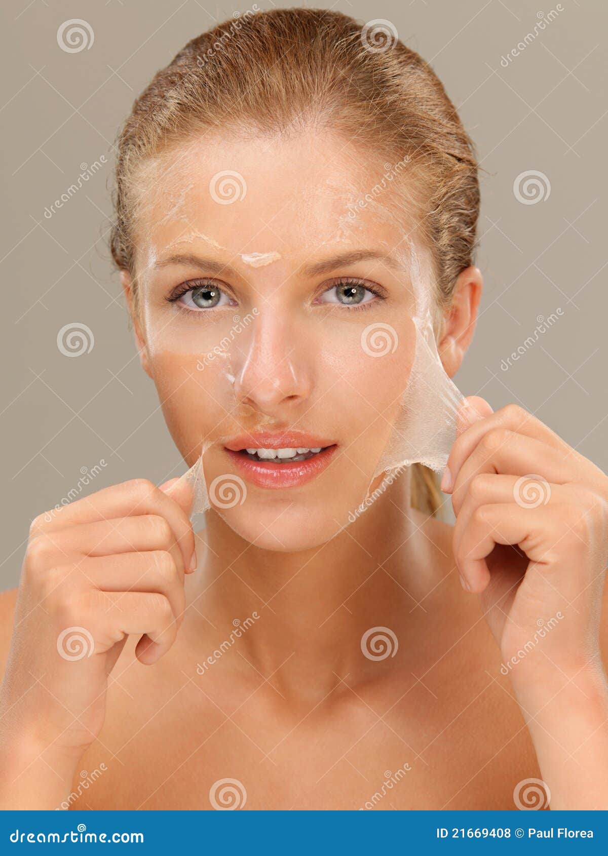 young woman peeling off a facial mask smiling